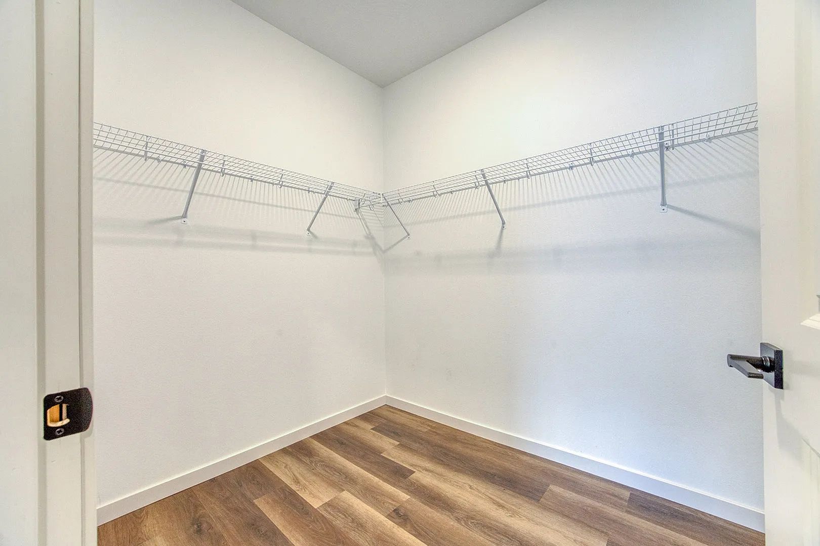 Spacious walk-in closet with sleek wooden floors and wire shelving for organized storage.