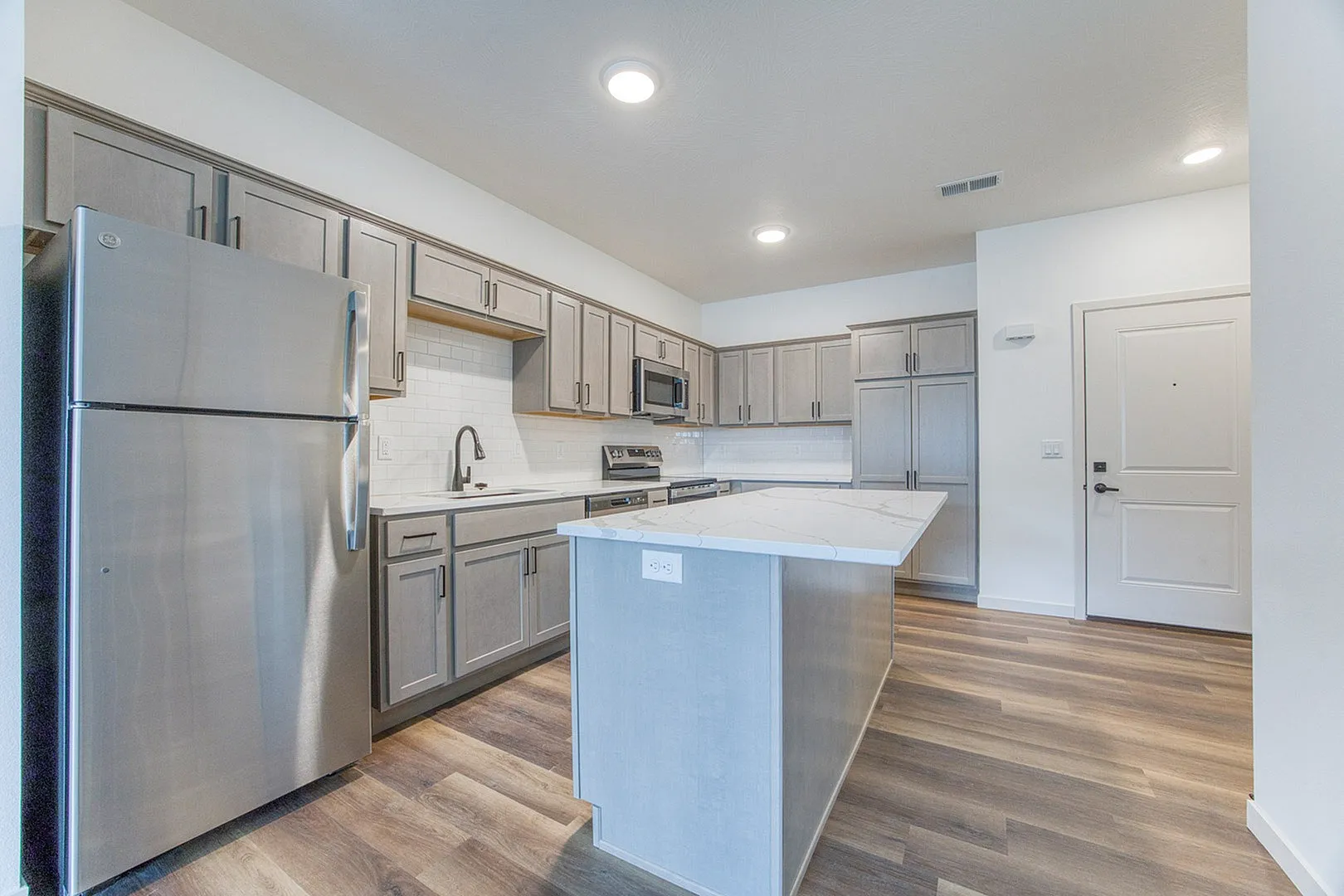 Modern kitchen with sleek cabinetry, stainless steel appliances, and a spacious island set against elegant hardwood flooring.