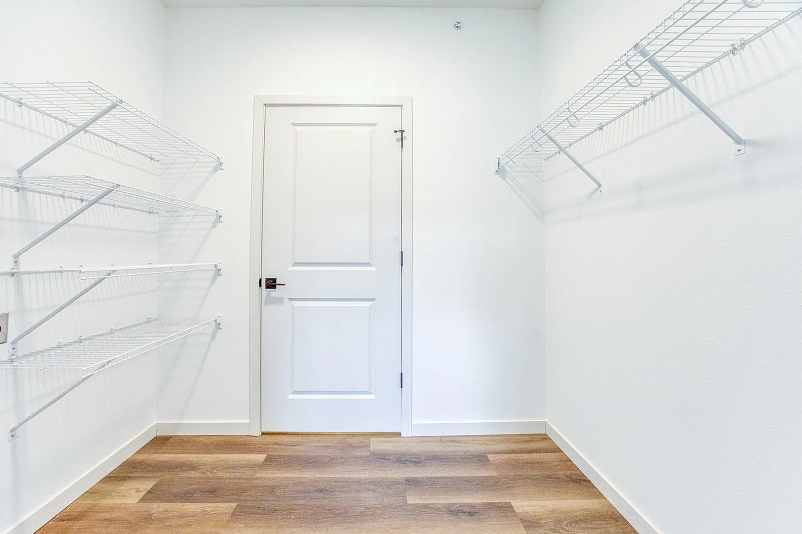Bright and spacious walk-in closet with sleek white shelving and modern design, perfect for organizing and storage.