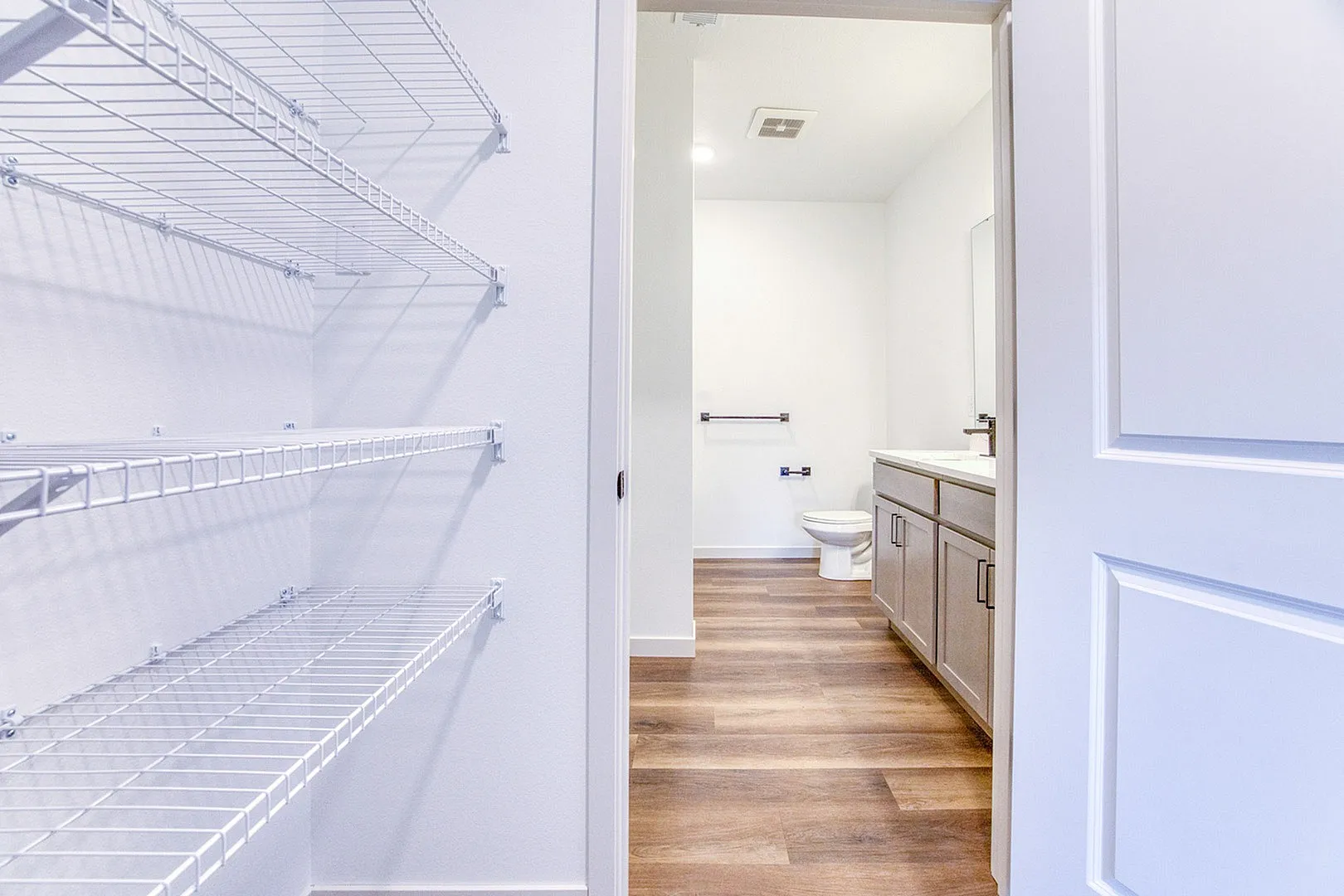 Bright and spacious bathroom with elegant wooden flooring and generous storage shelves, offering a modern and inviting atmosphere.