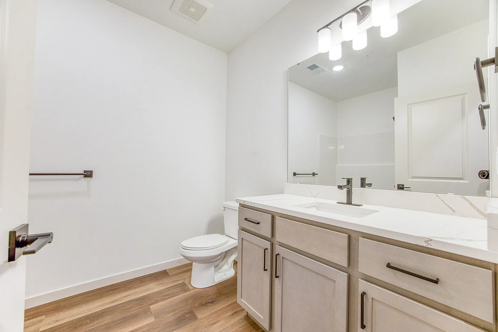 Bright modern bathroom featuring elegant vanity, sleek faucet, and warm wood flooring.