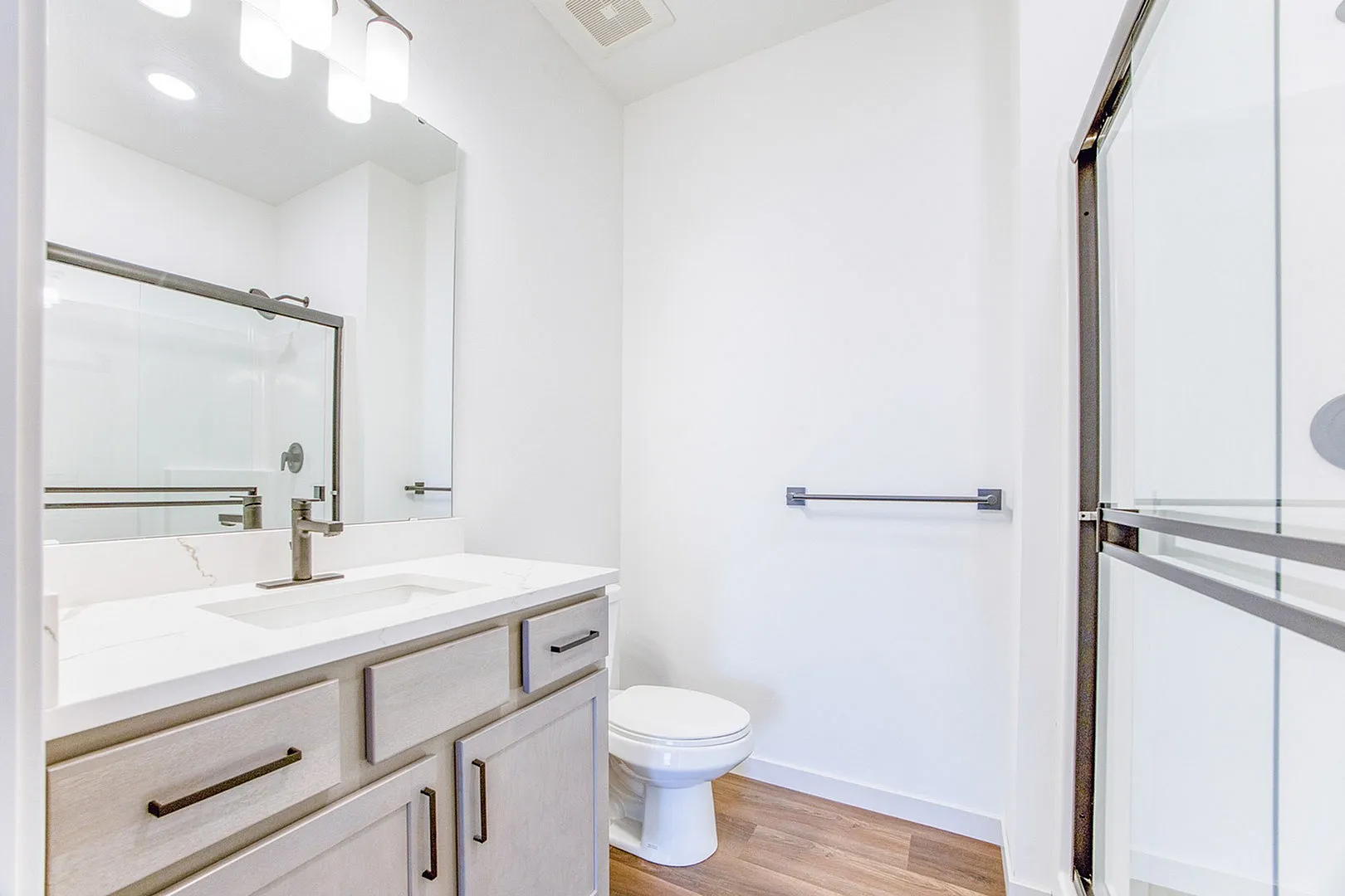 Bright and modern bathroom featuring sleek marble countertops, elegant fixtures, and a spacious shower.