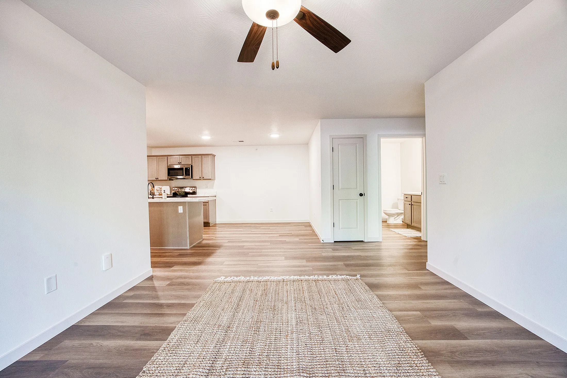 Elegant open-concept living space with modern kitchen view and stylish wood flooring, ideal for comfortable living.