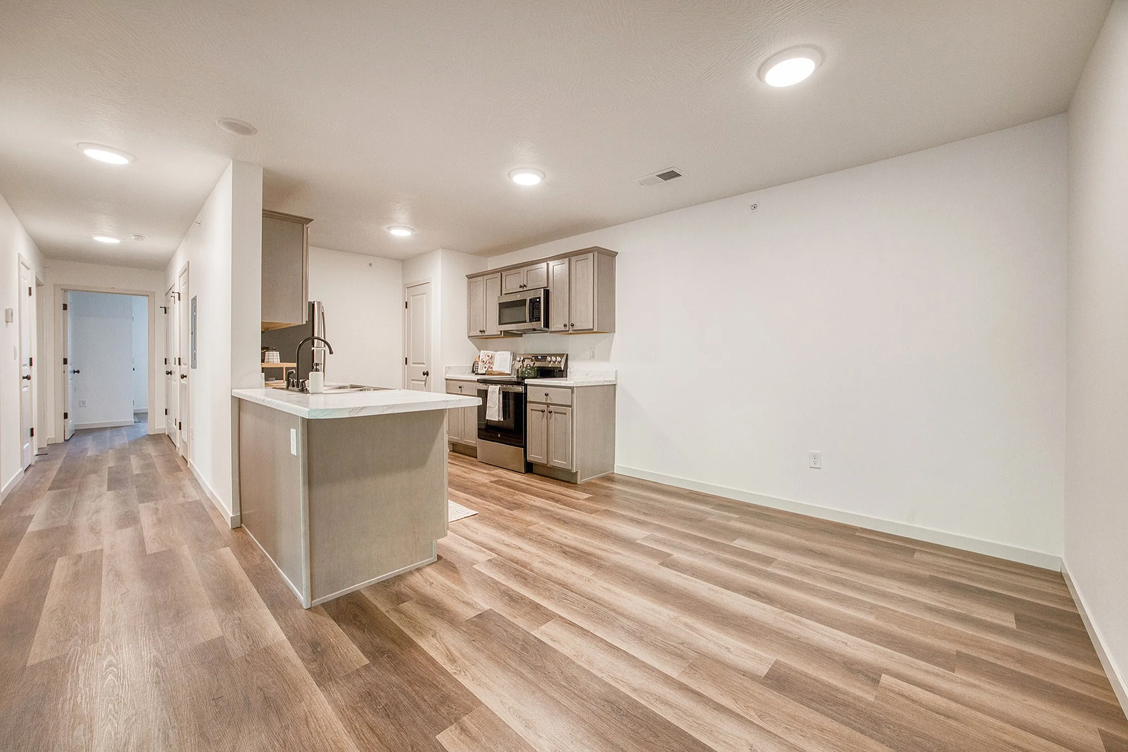 Modern kitchen with sleek cabinets, marble countertops, and stylish hardwood flooring in an open-concept apartment layout.