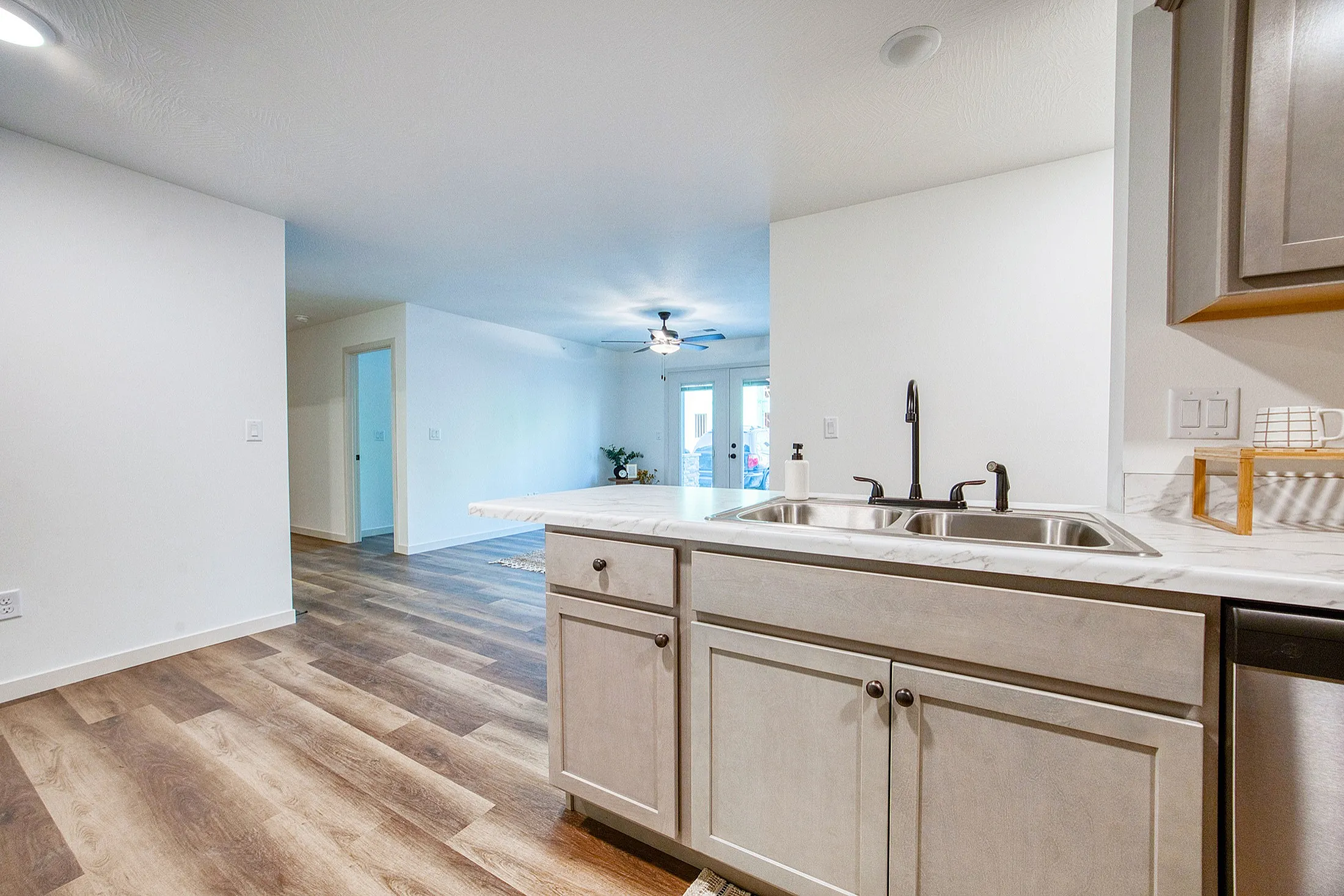 Bright open-concept kitchen with modern fixtures and seamless transition to a spacious living area featuring elegant wood flooring.