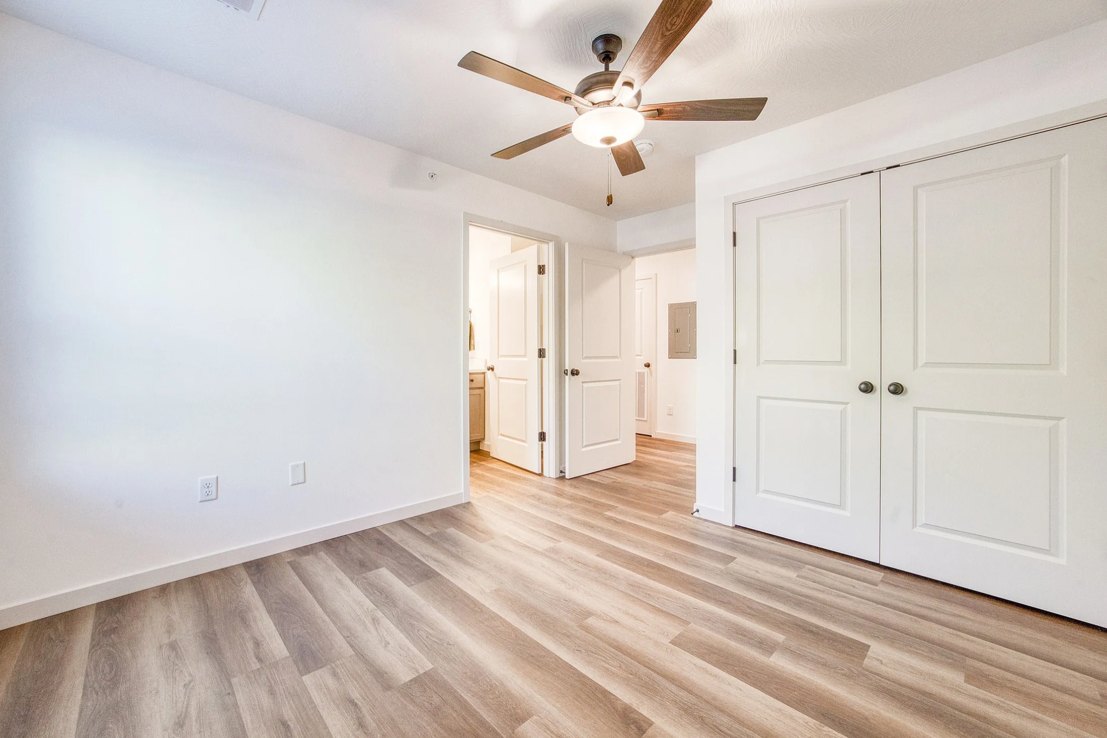Spacious and bright room with elegant wood floors, modern ceiling fan, and ample closet space.