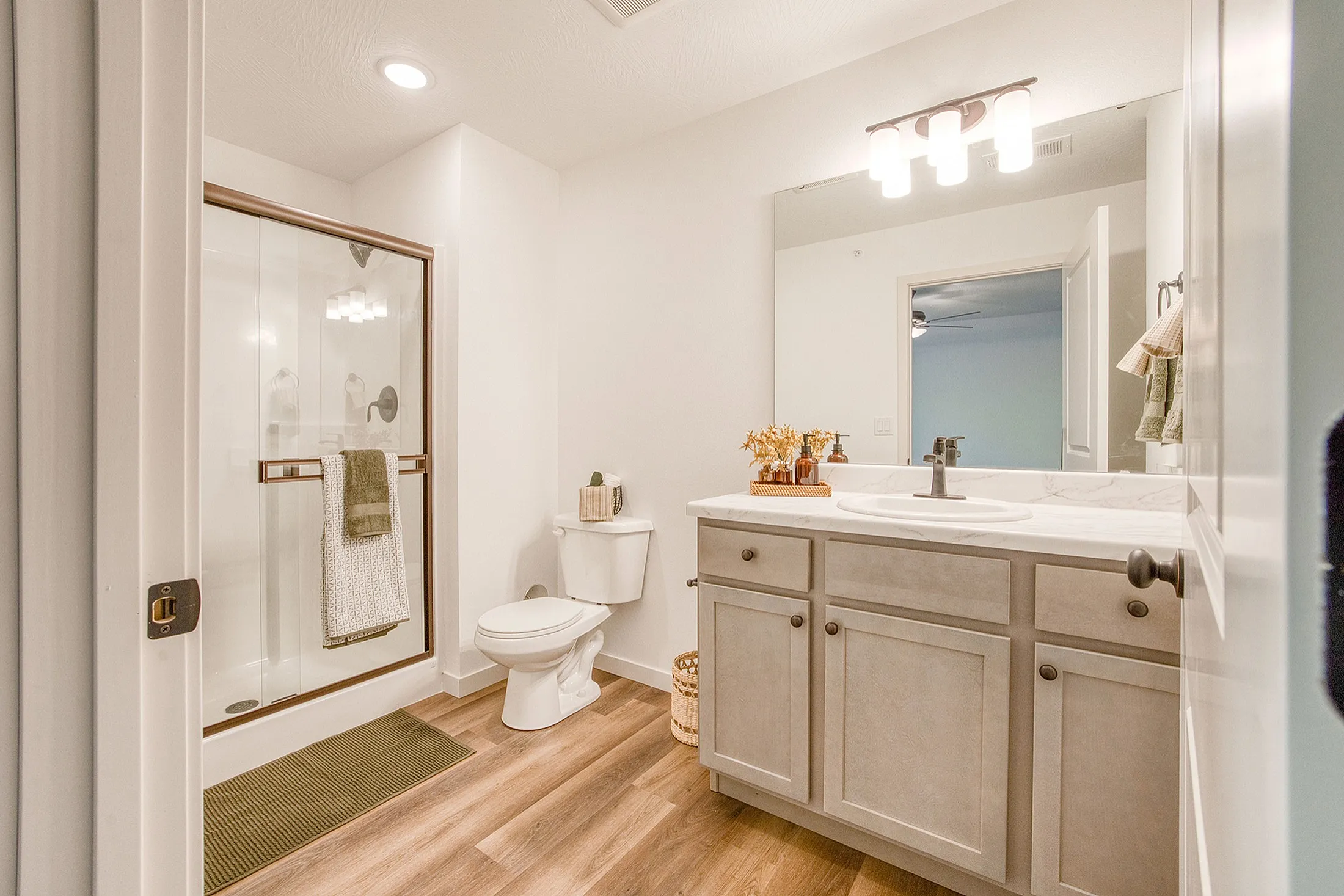 Elegant bathroom with modern shower, sleek vanity, and warm wood flooring, offering a serene and stylish retreat.