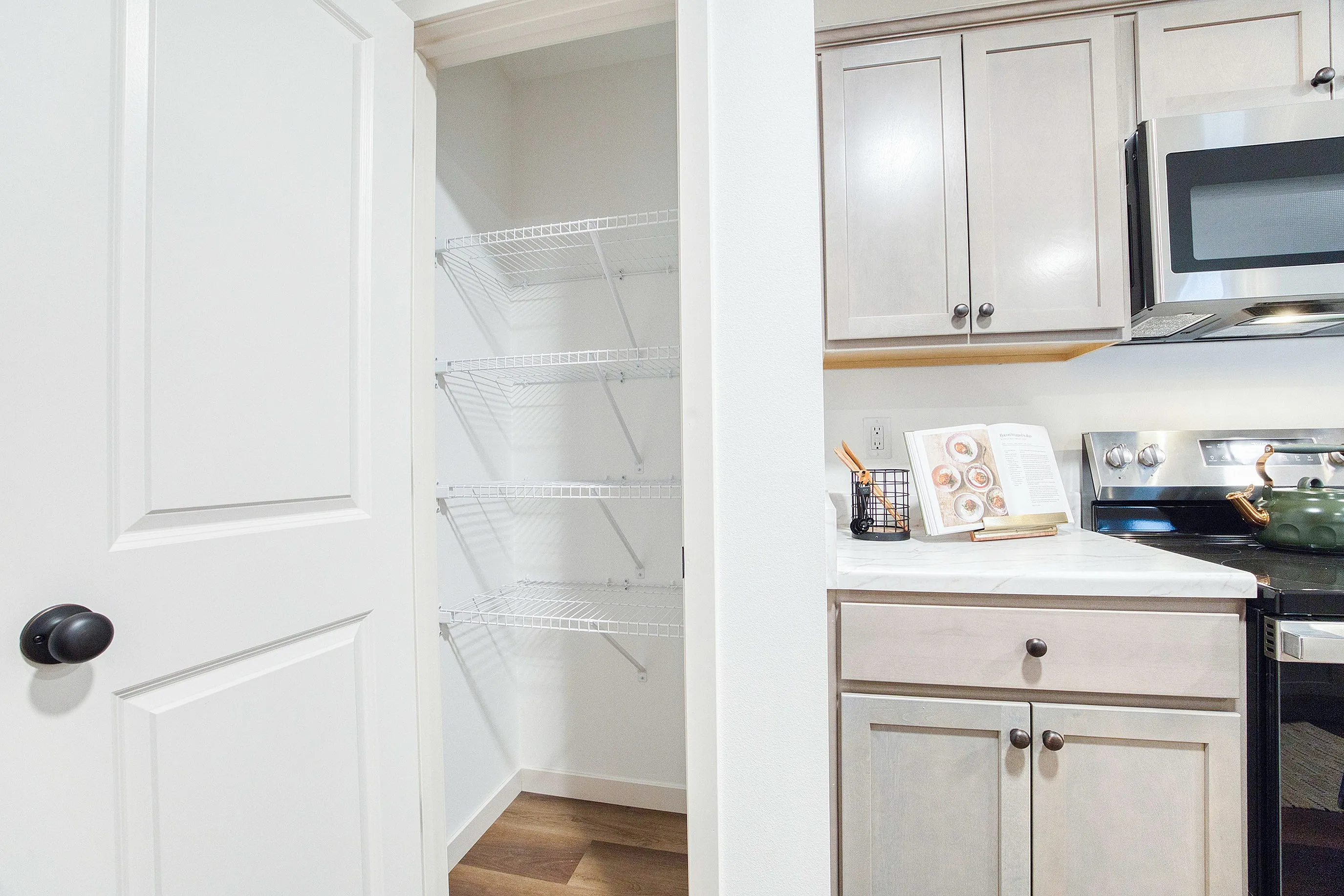 Bright kitchen corner with elegant cabinetry, modern appliances, and an open pantry, offering functional and stylish storage solutions.