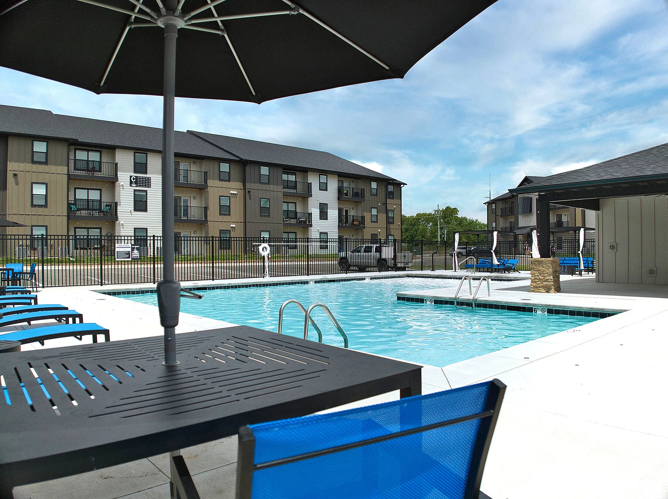 Inviting apartment complex with a luxurious swimming pool and modern seating area, perfect for relaxation and leisure.