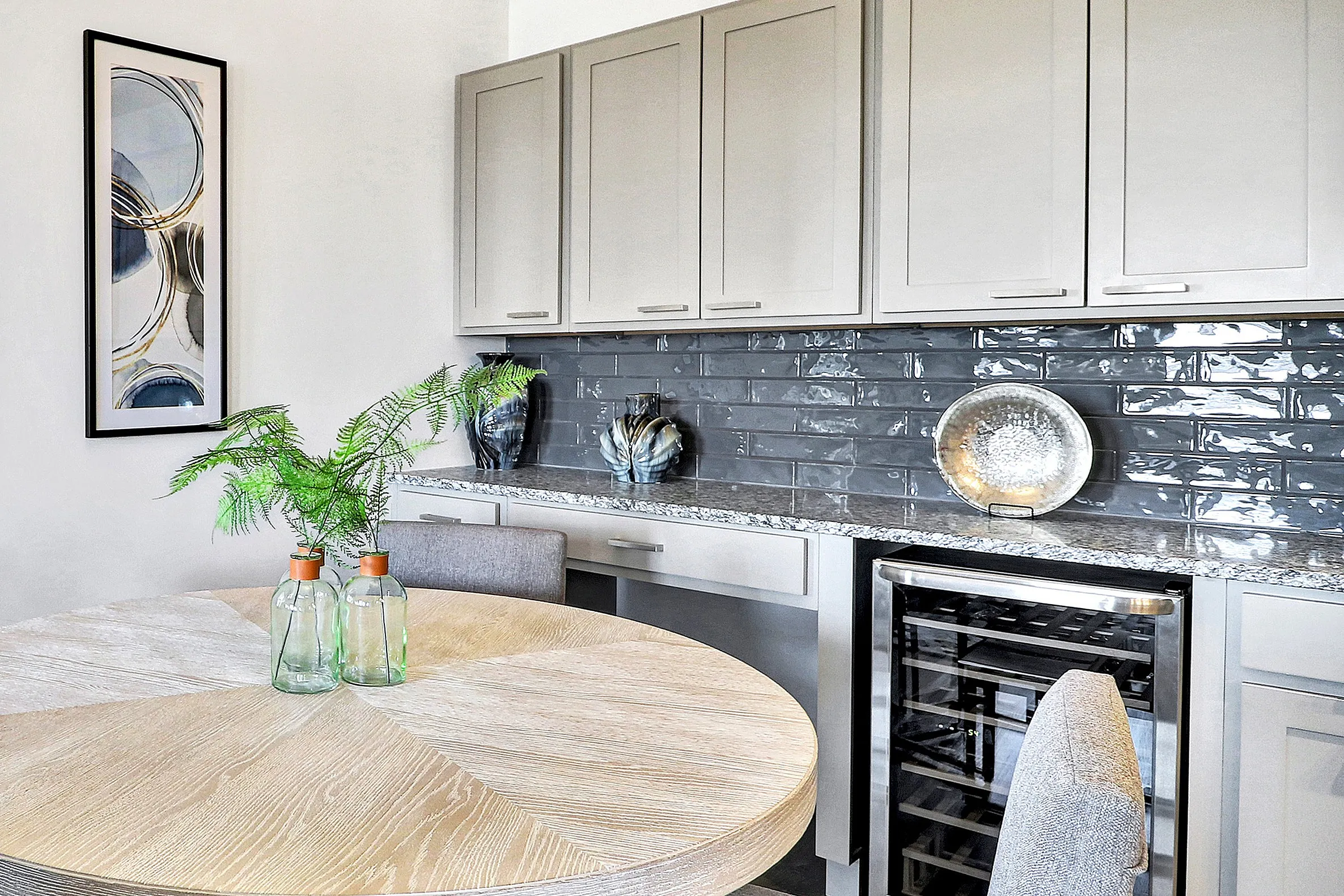 Chic modern kitchen with elegant cabinetry, stylish round dining table, and plush chairs, exuding contemporary charm and sophistication.