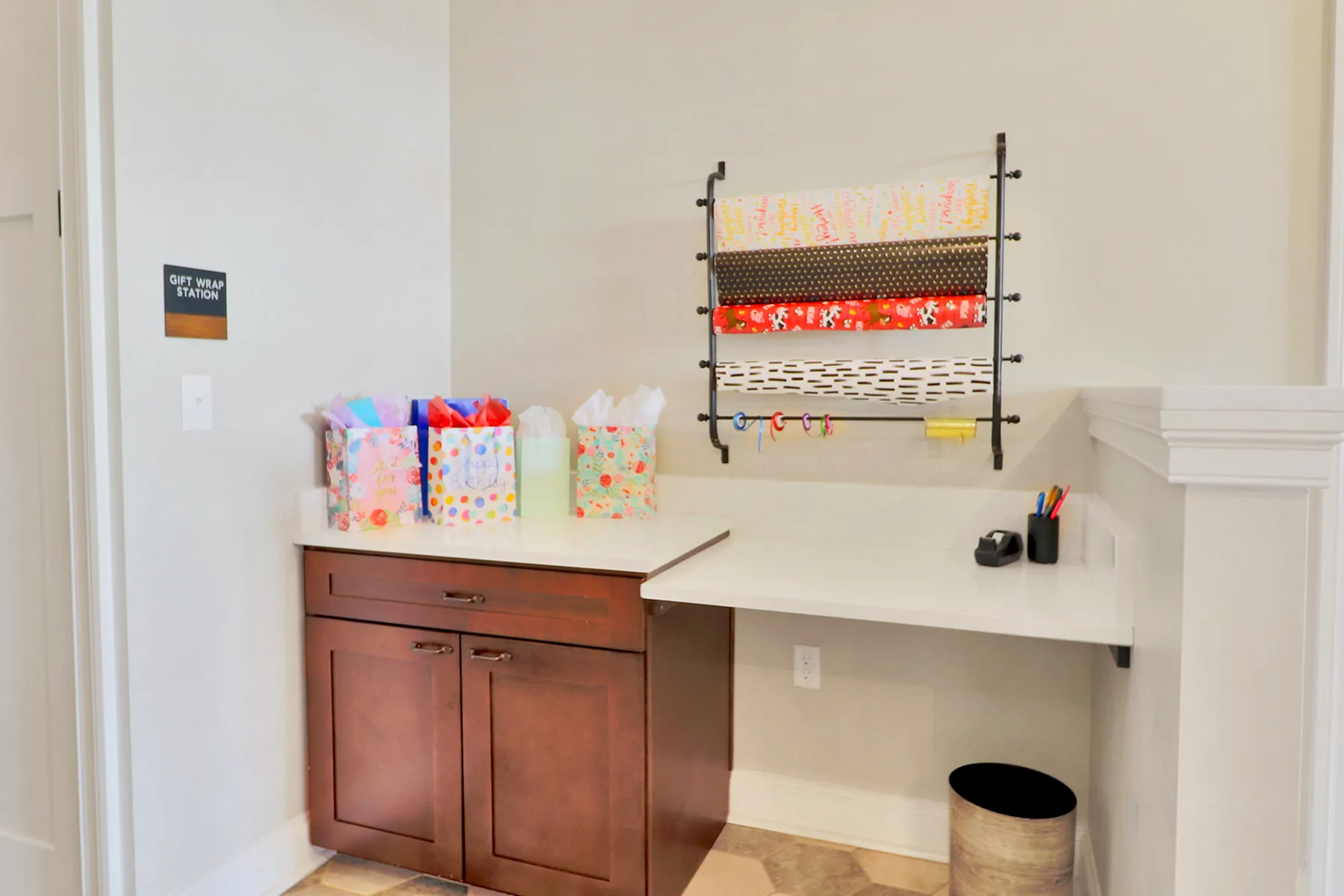 Chic gift wrap station with vibrant wrapping paper rolls, colorful gift bags, and sleek cabinetry, perfect for thoughtful occasions.