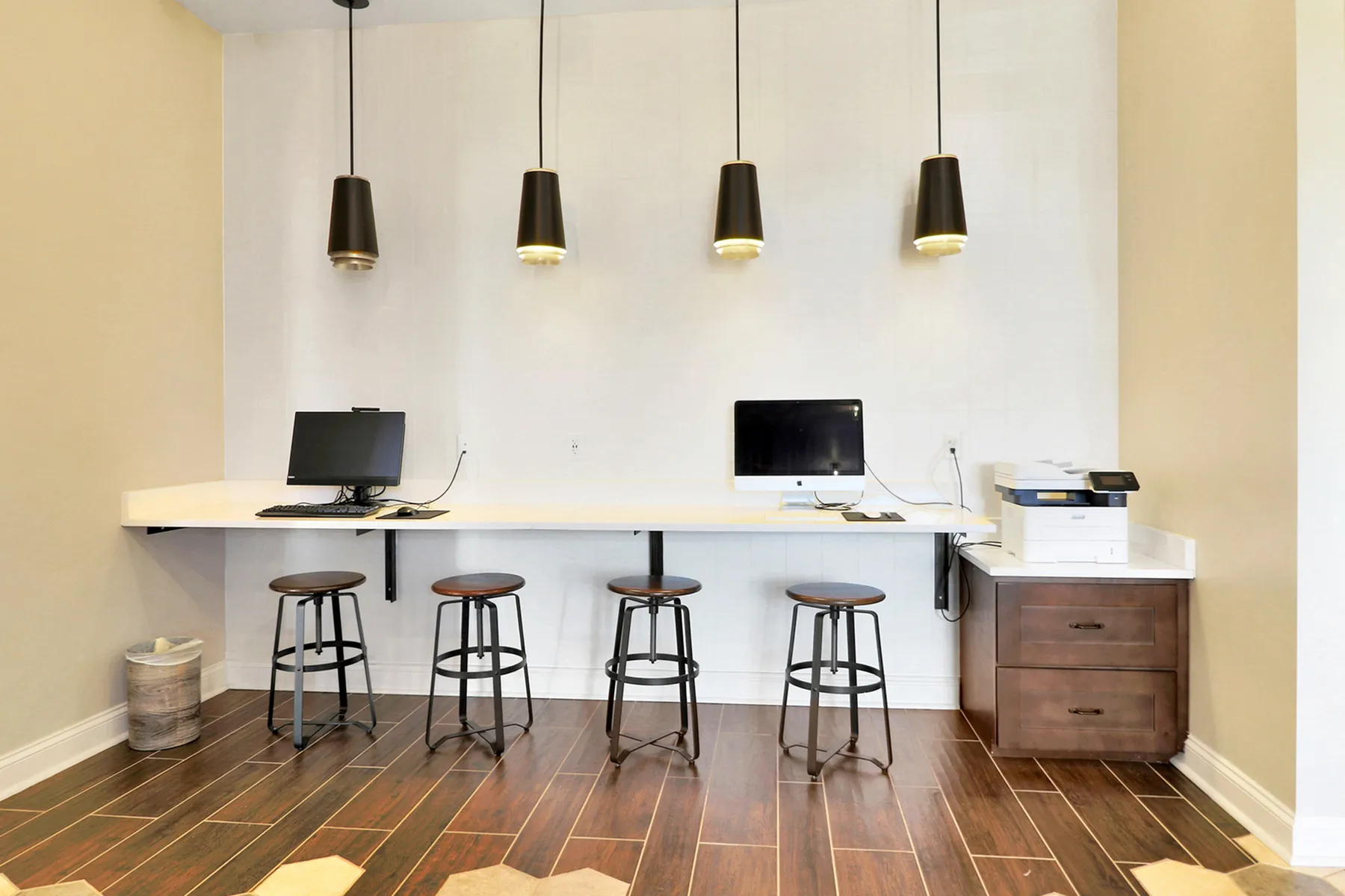 Modern workspace with sleek computers, stylish bar stools, and contemporary pendant lighting, perfect for productivity and collaboration.