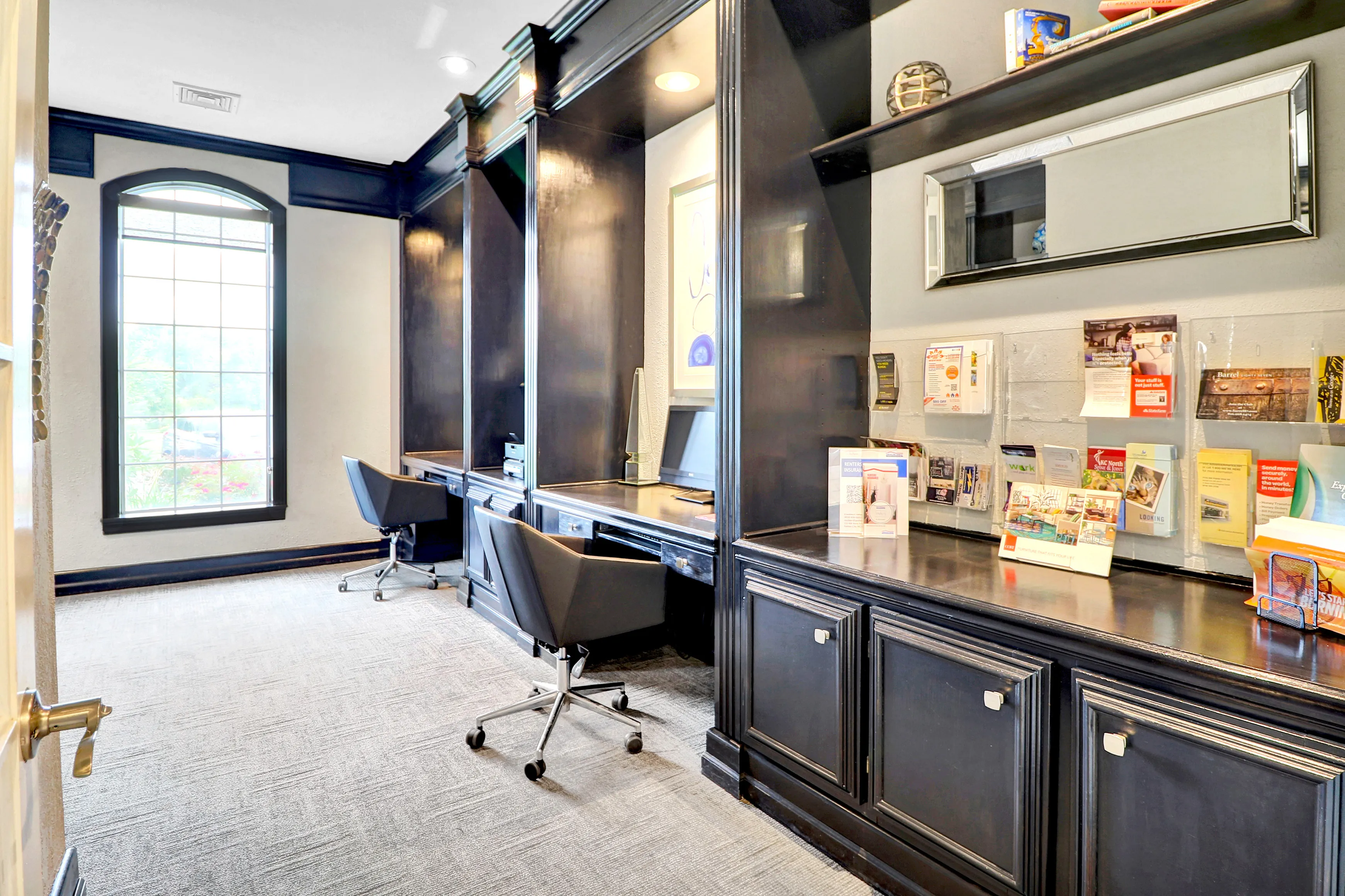 Sophisticated office space with elegant dark wood cabinetry, modern chairs, and ample natural light from large windows.
