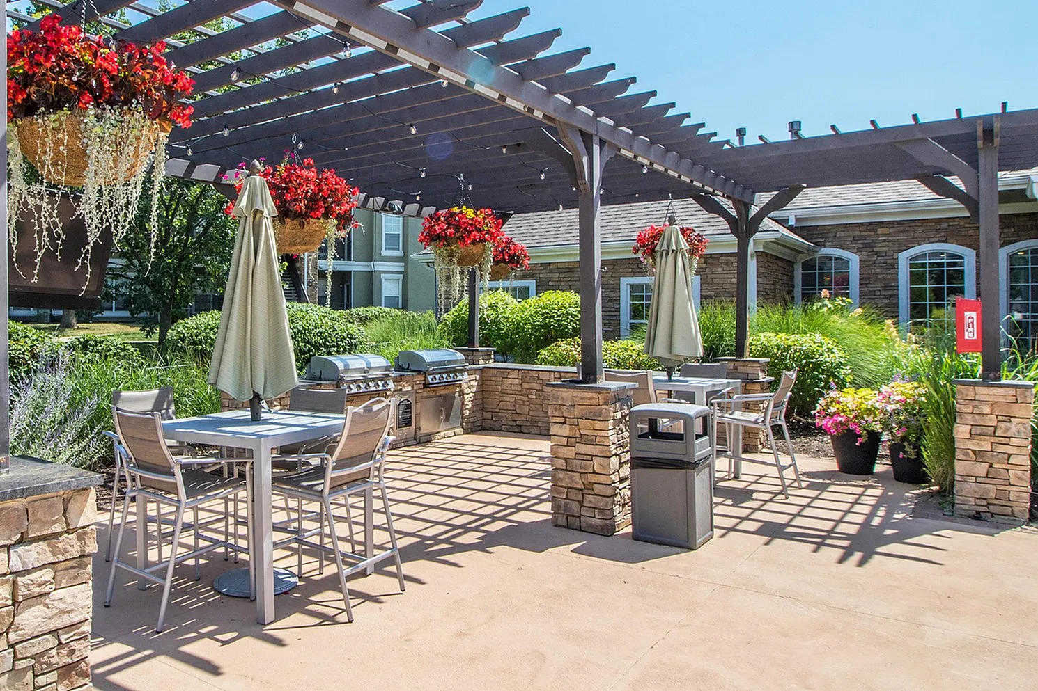 Charming outdoor patio with elegant pergola, vibrant hanging flowers, and modern dining area, perfect for relaxation and gathering.