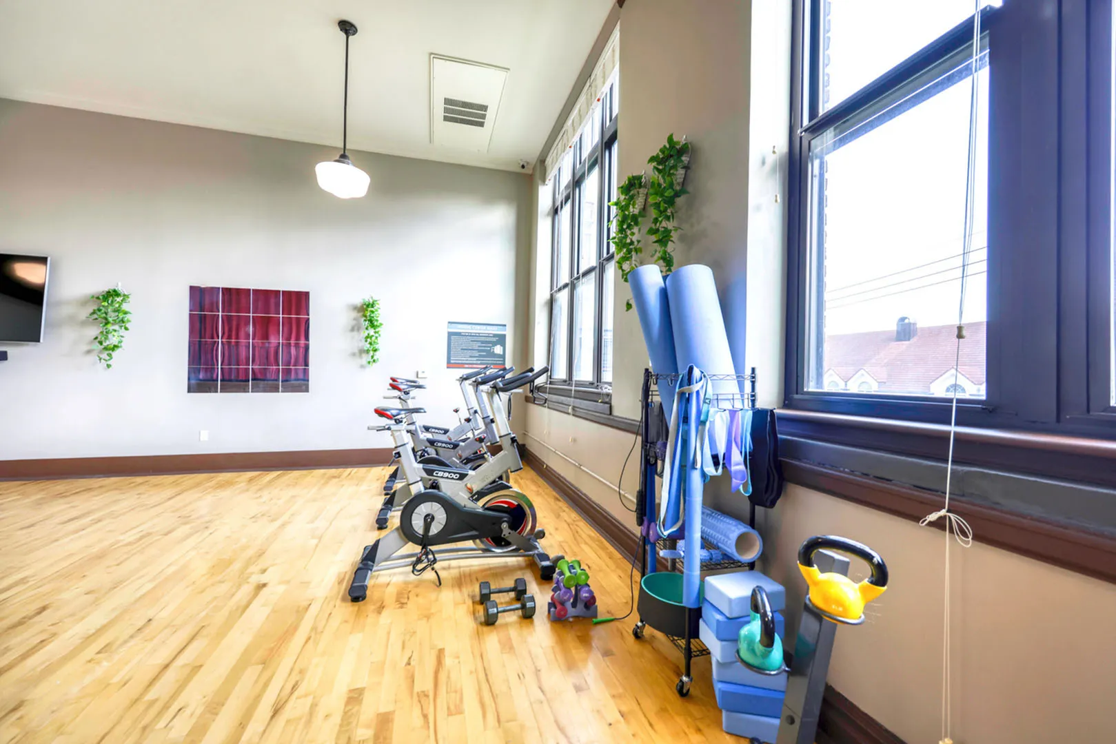 Bright and spacious fitness room featuring stationary bikes, yoga mats, and exercise equipment, with large windows and stylish decor.