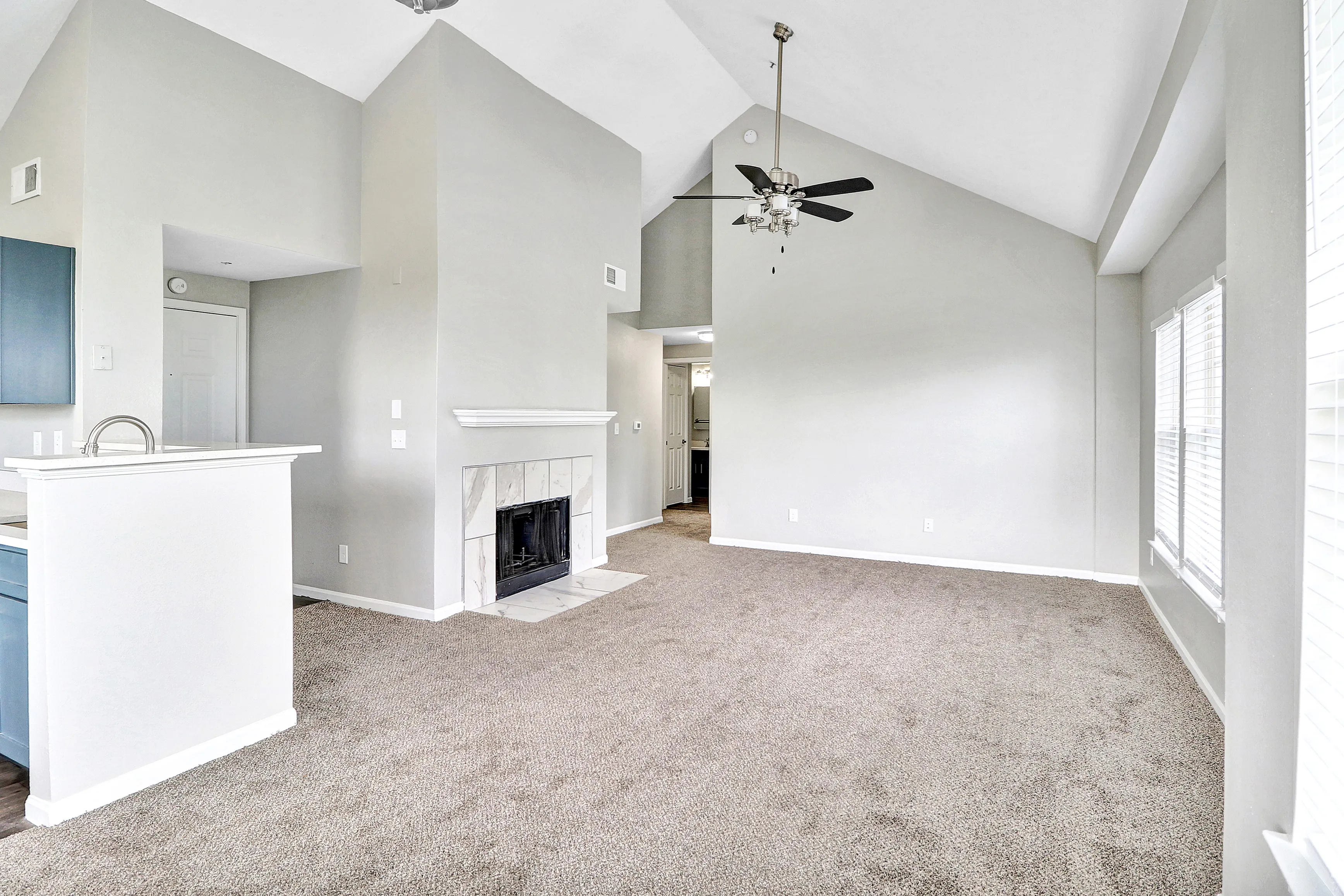 Bright and airy living room featuring vaulted ceilings, cozy fireplace, and plush carpeting with abundant natural light.