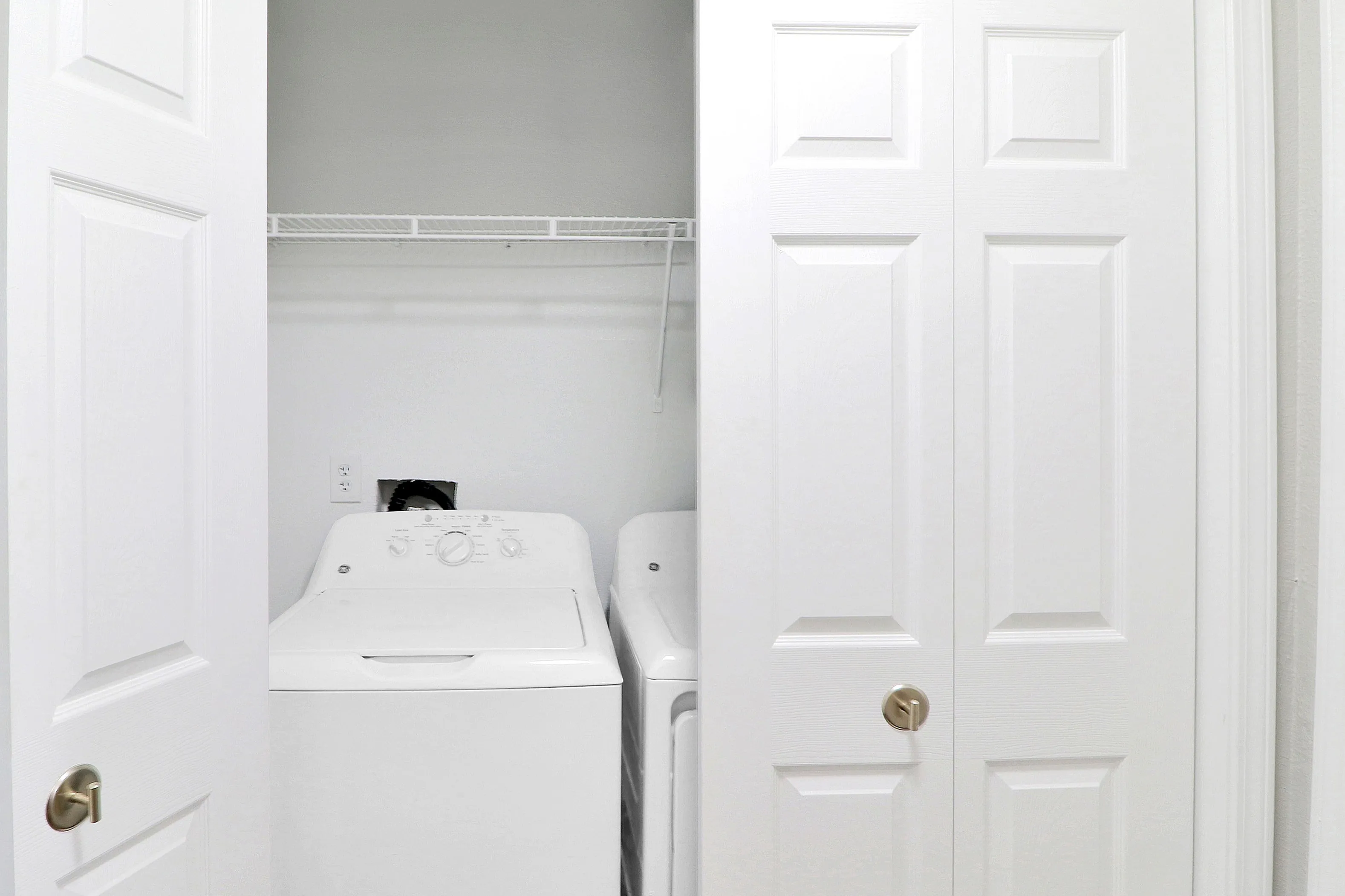 Convenient laundry nook with modern washer and dryer, neatly tucked behind white double doors.