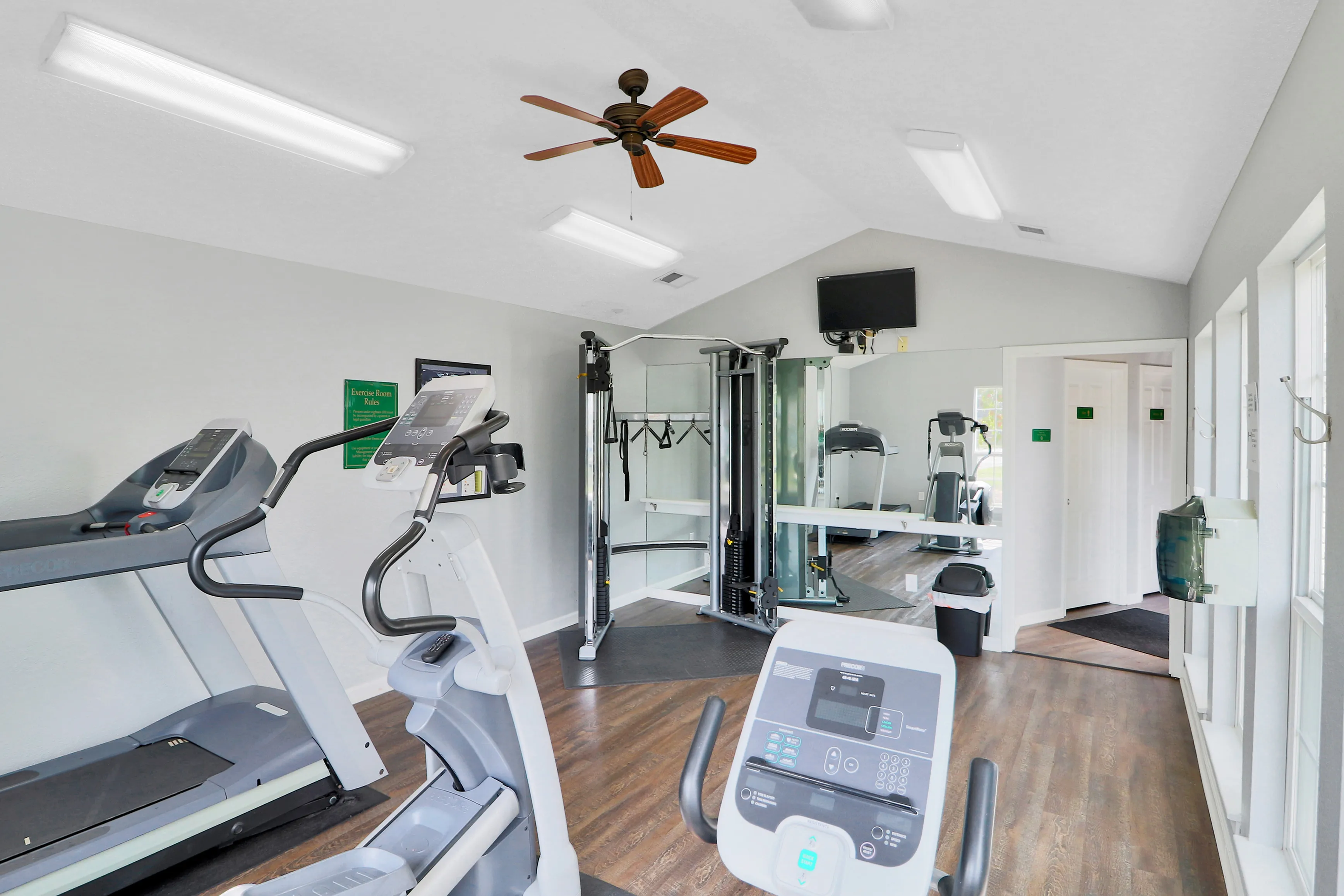 Bright and inviting gym with modern exercise equipment, including treadmills and strength machines, set on a sleek hardwood floor.