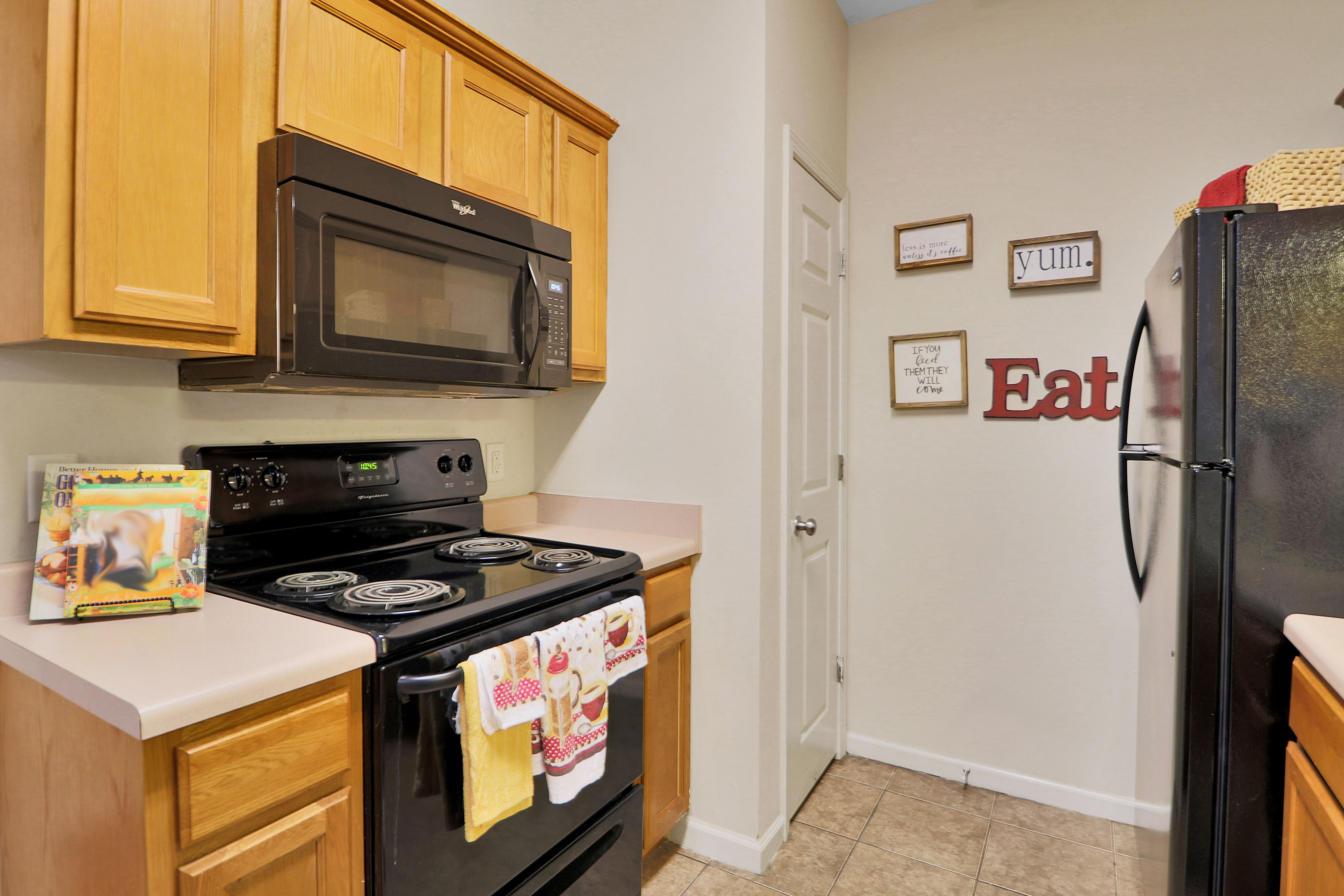 Charming kitchen with modern appliances, wood cabinets, and decorative wall art creating a cozy atmosphere.