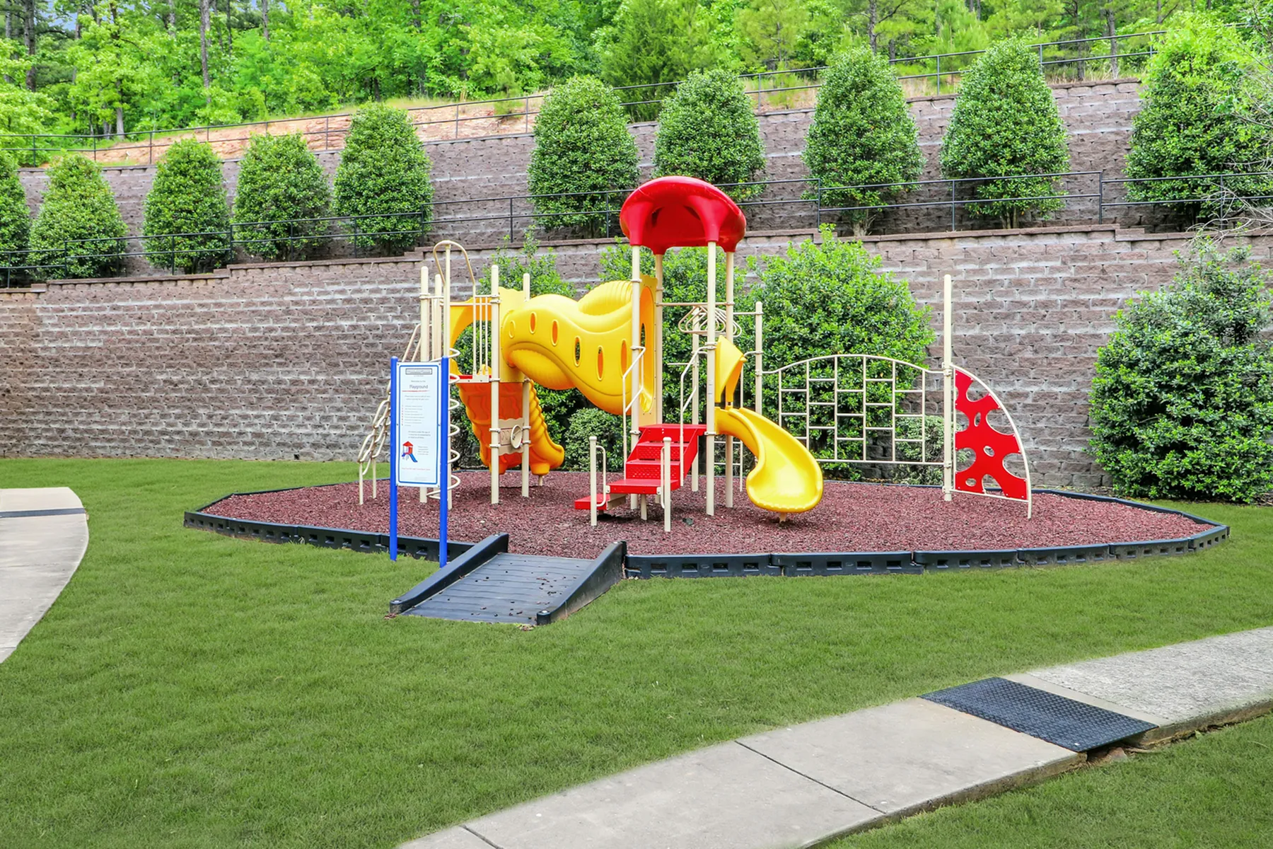 Inviting outdoor playground with vibrant yellow and red slides, surrounded by lush greenery, providing a perfect space for family fun.