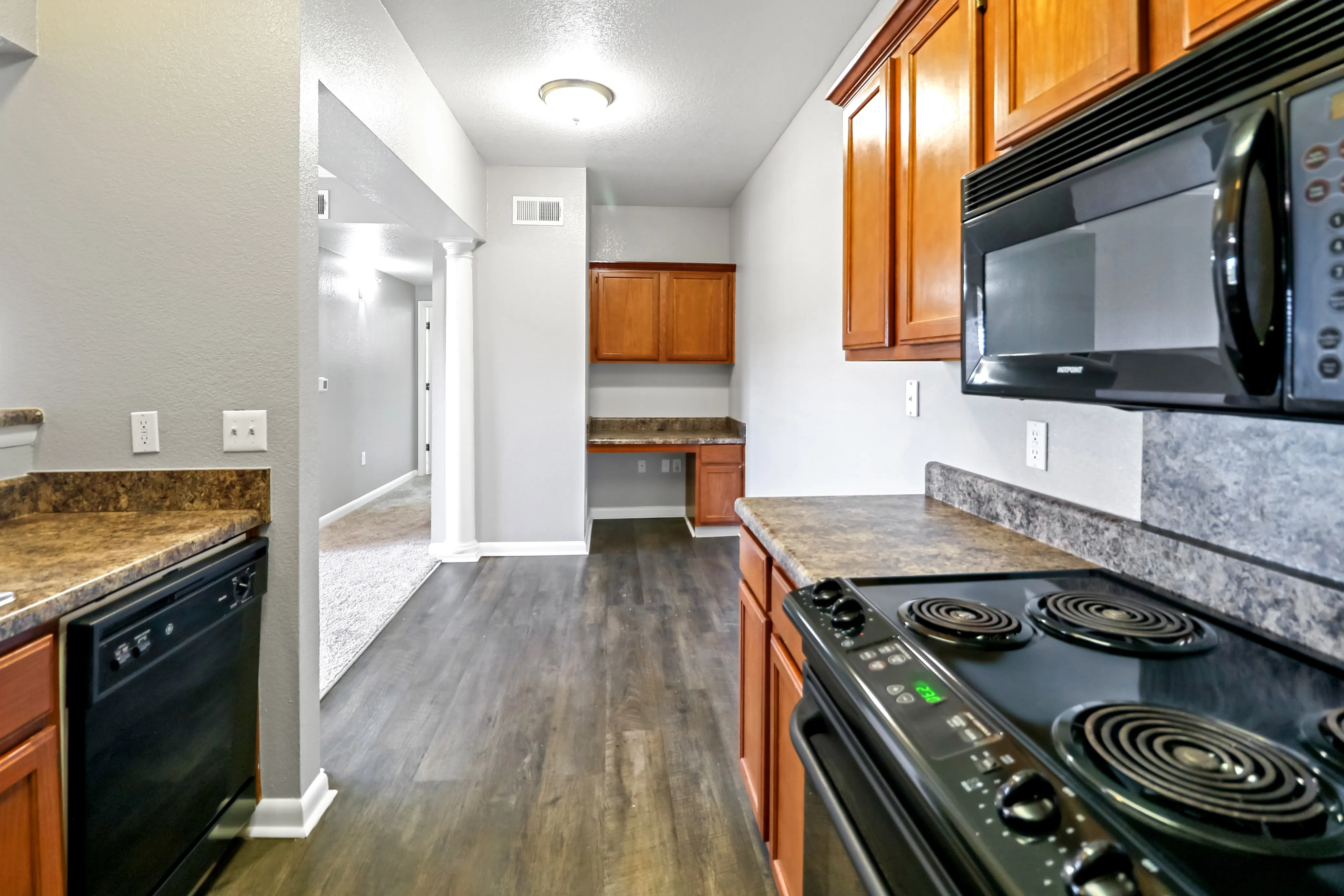 Modern kitchen with sleek appliances, elegant cabinetry, and stylish countertops leading to an inviting open hallway.