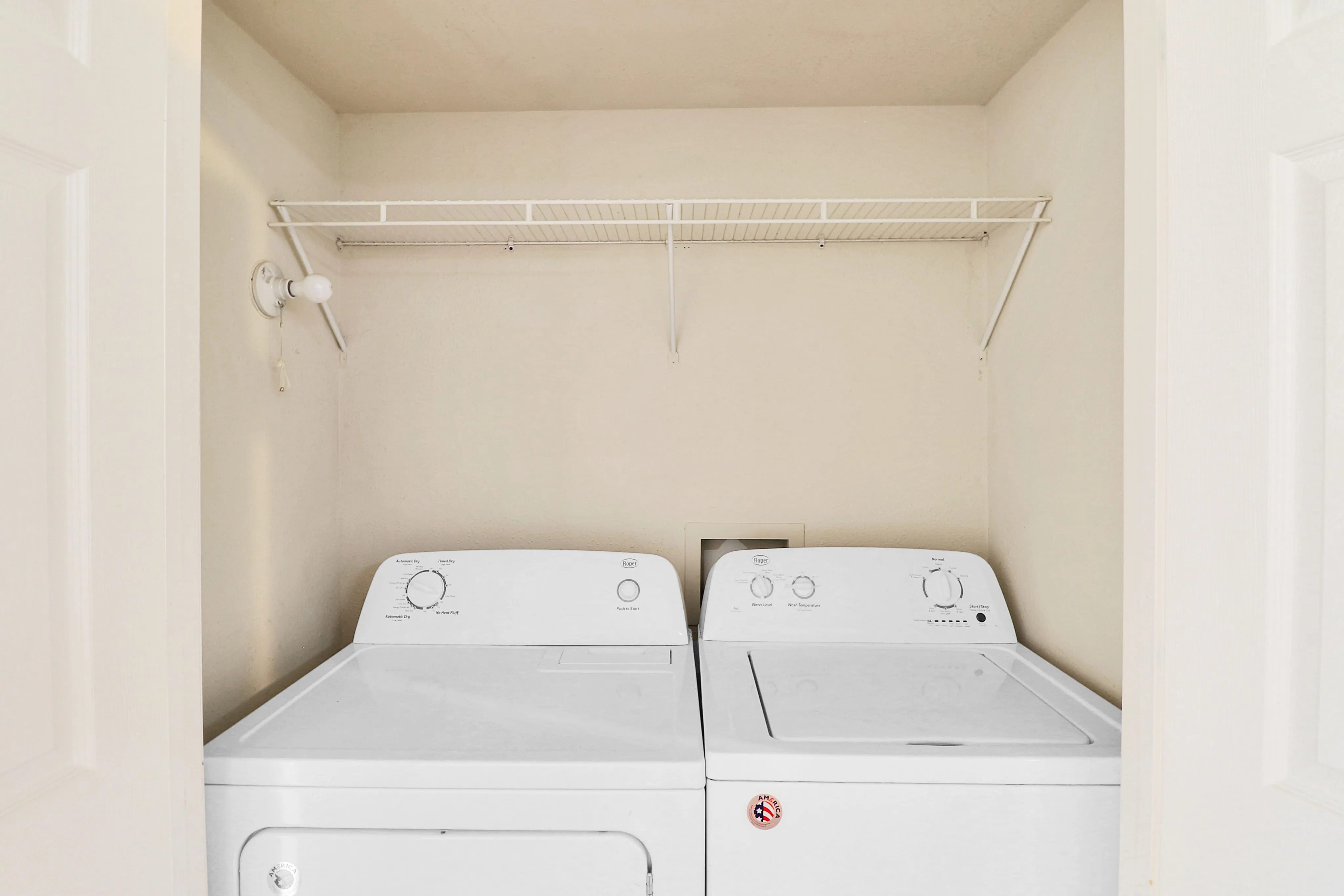 Inviting laundry nook featuring a modern washer and dryer set under a convenient storage shelf.