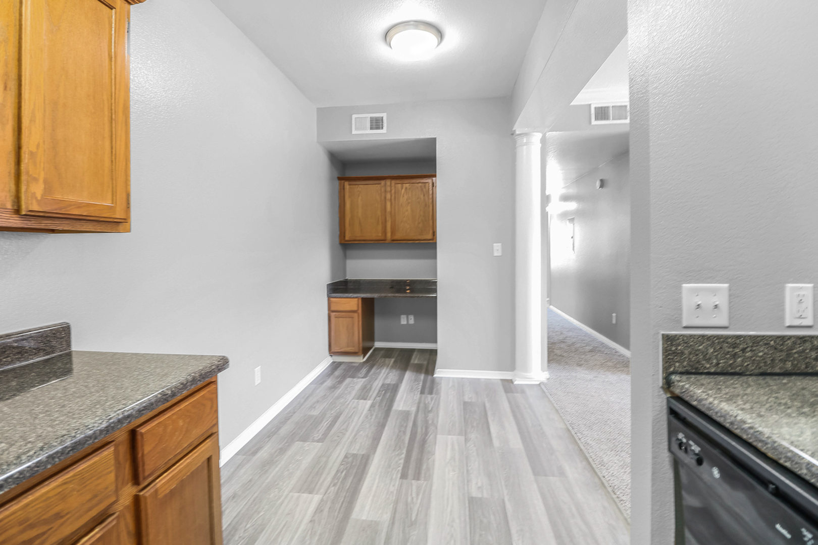 Chic kitchen space with elegant wood cabinetry, sleek countertops, and modern flooring in a spacious apartment.
