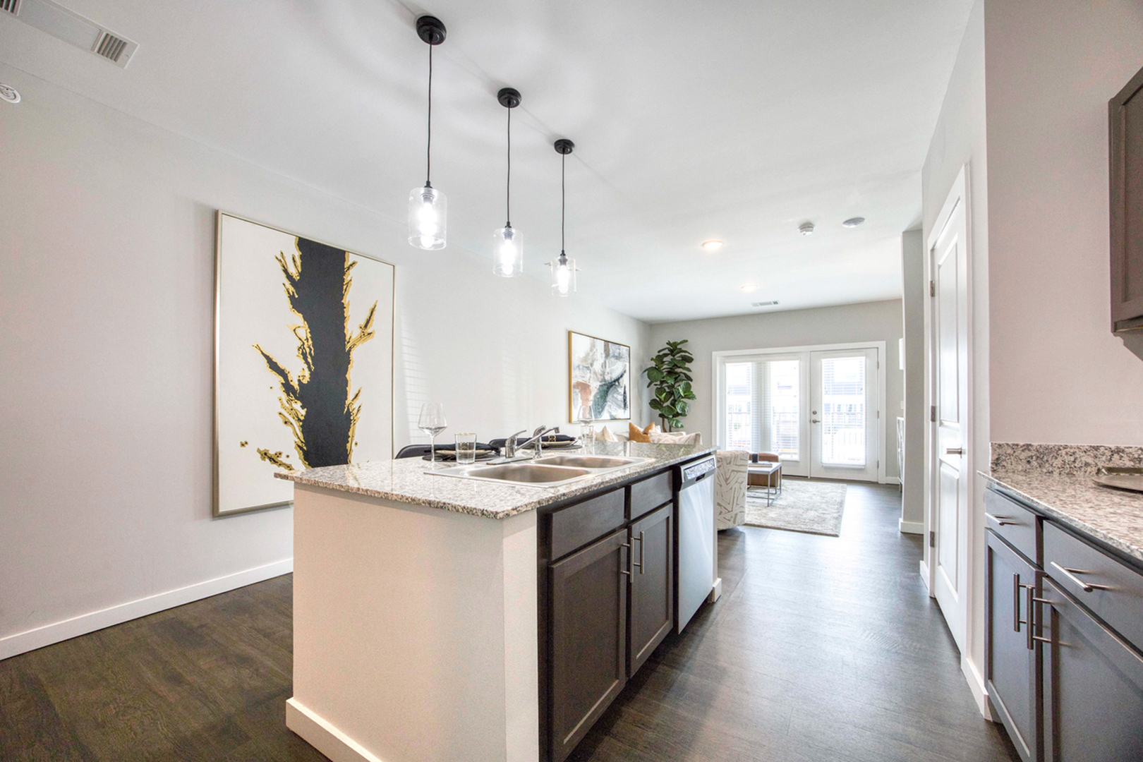 Modern open-concept kitchen with sleek granite countertops, elegant pendant lighting, and an inviting living area with abundant natural light.