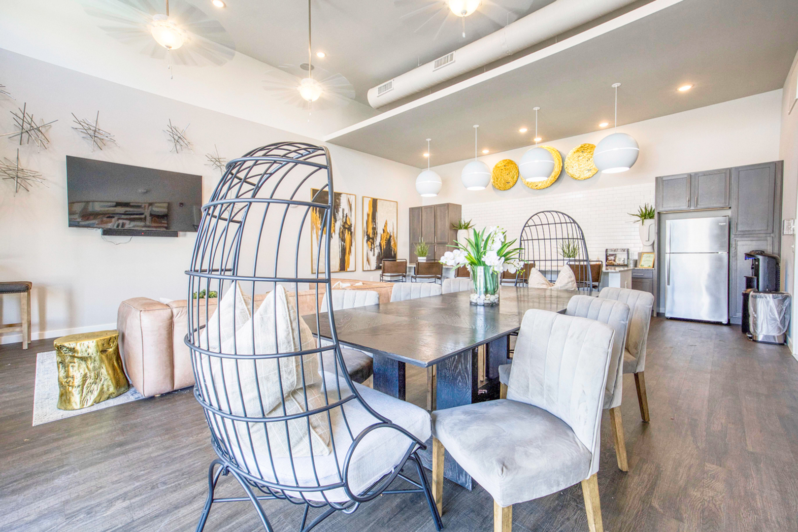 Modern open-concept dining area featuring contemporary seating, stylish pendant lighting, and a sleek stainless steel fridge, perfect for entertaining.