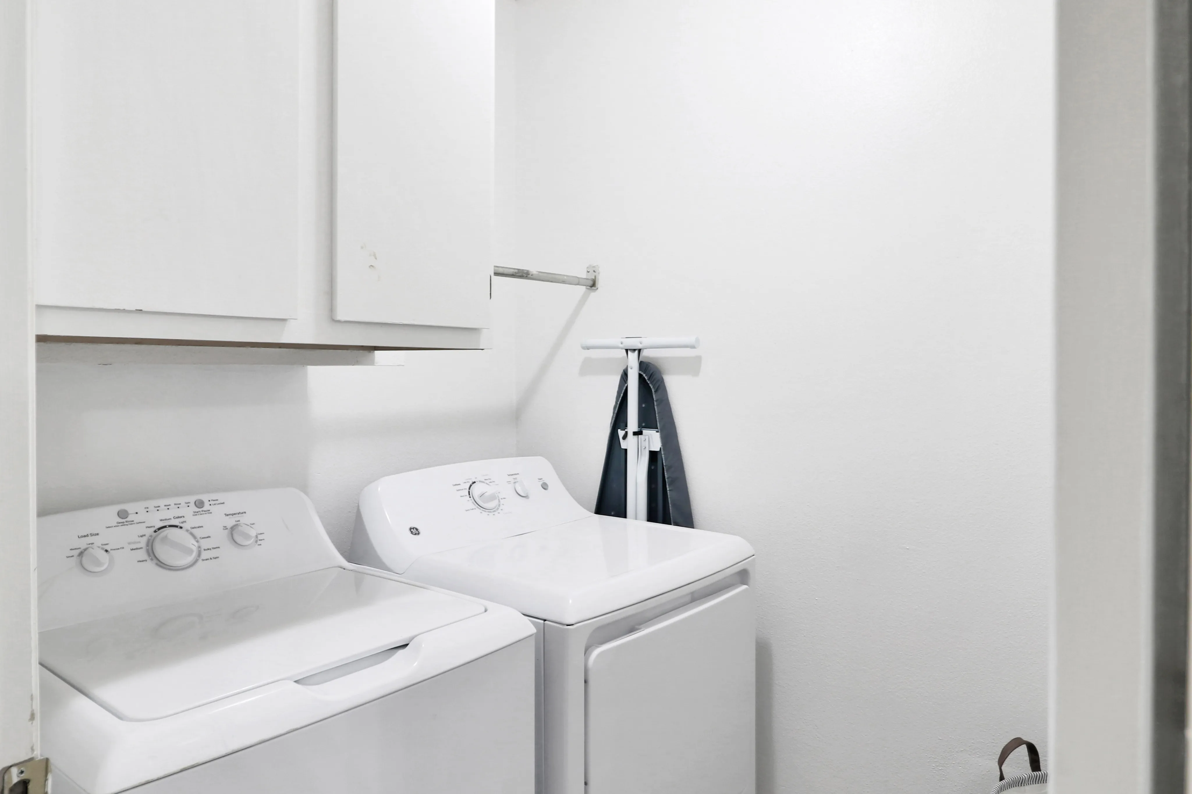 Bright and efficient laundry room with modern washer and dryer, ample storage cabinets, and convenient ironing station.