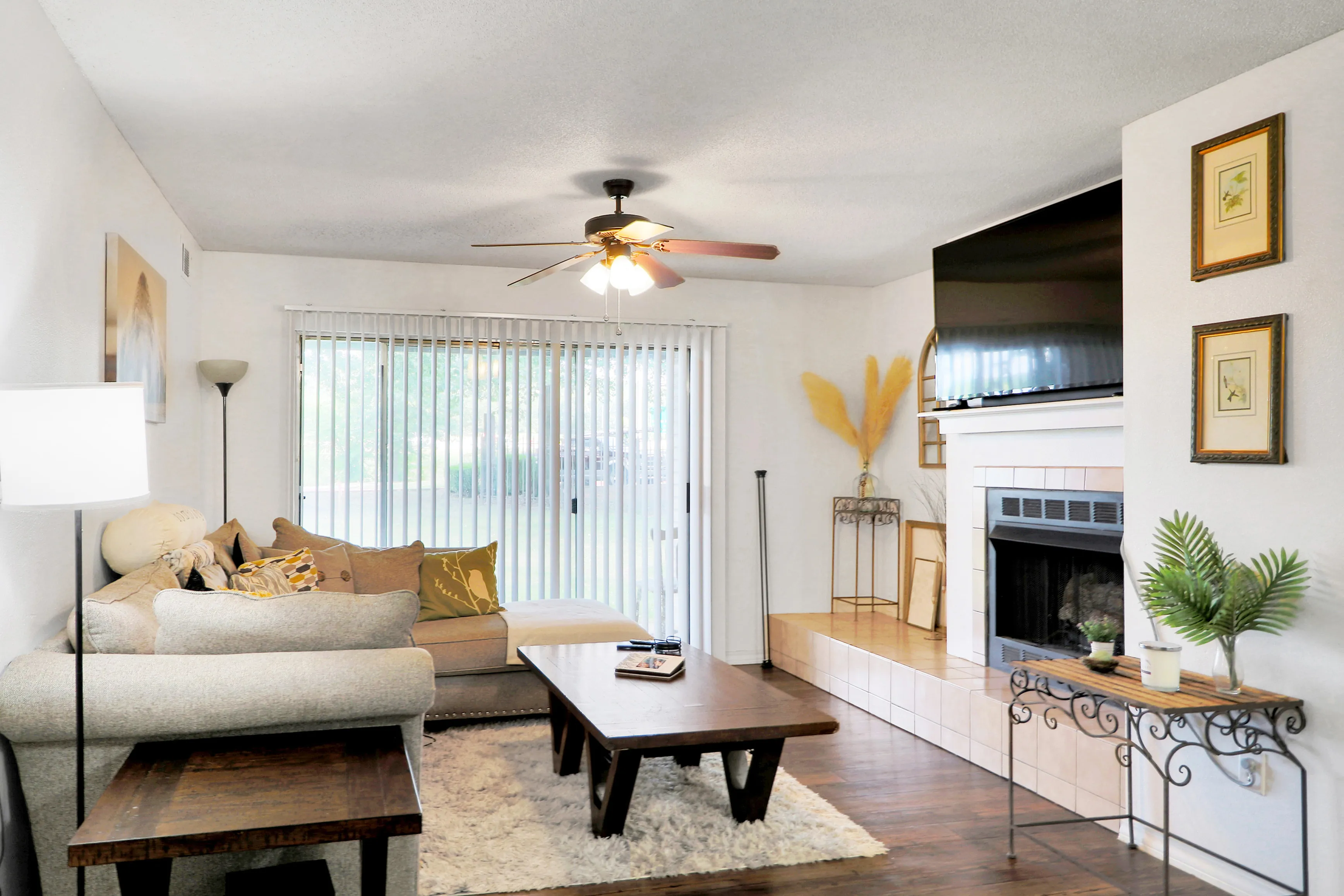 Charming living room with cozy seating, large TV, and a stylish fireplace, featuring abundant natural light and elegant decor.