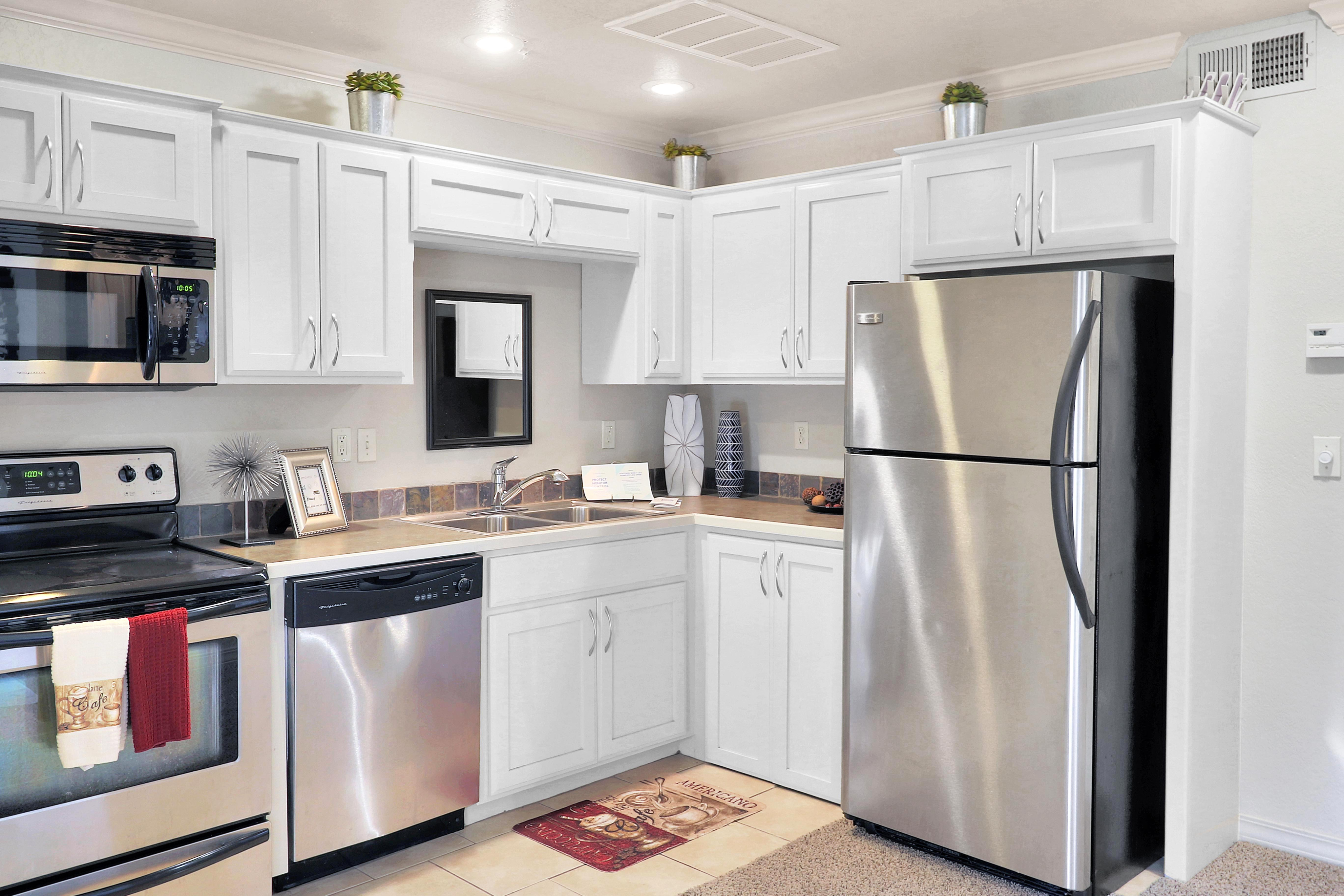 Modern kitchen with sleek stainless steel appliances, white cabinetry, and elegant decor accents.