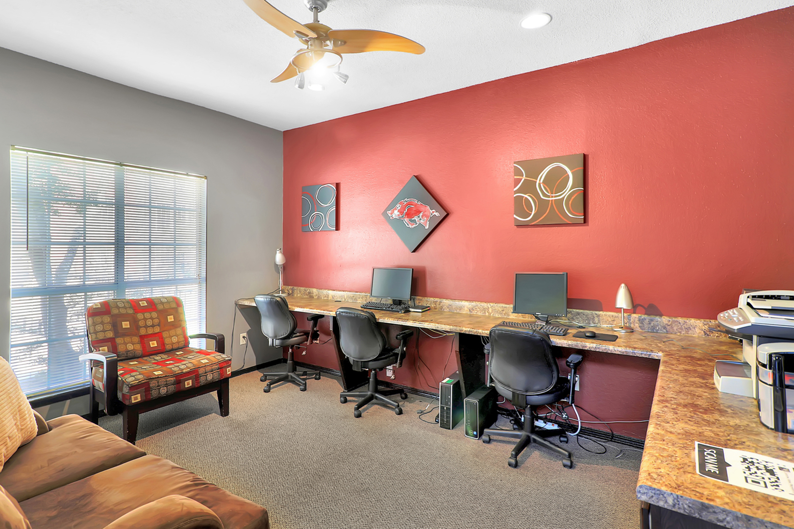 Bright and inviting office space with modern furnishings, featuring stylish red accent walls, comfortable seating, and sleek workstations.