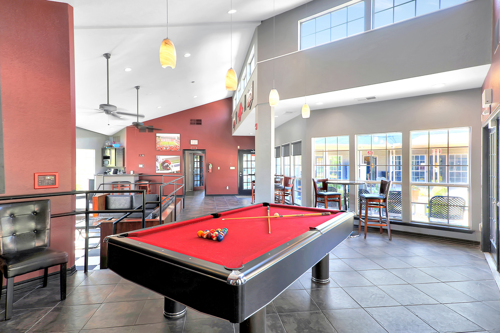 Inviting recreation room with a vibrant red pool table, modern lighting, and ample seating space, perfect for leisure and entertainment.