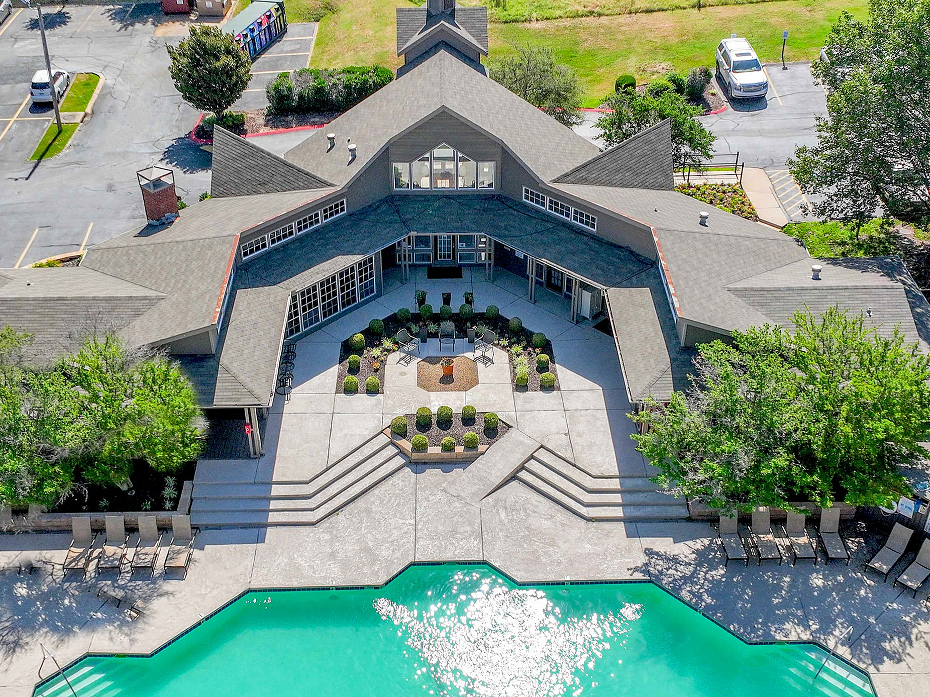 Breathtaking aerial view of a luxurious apartment community featuring a sparkling pool, lush greenery, and ample seating for relaxation.