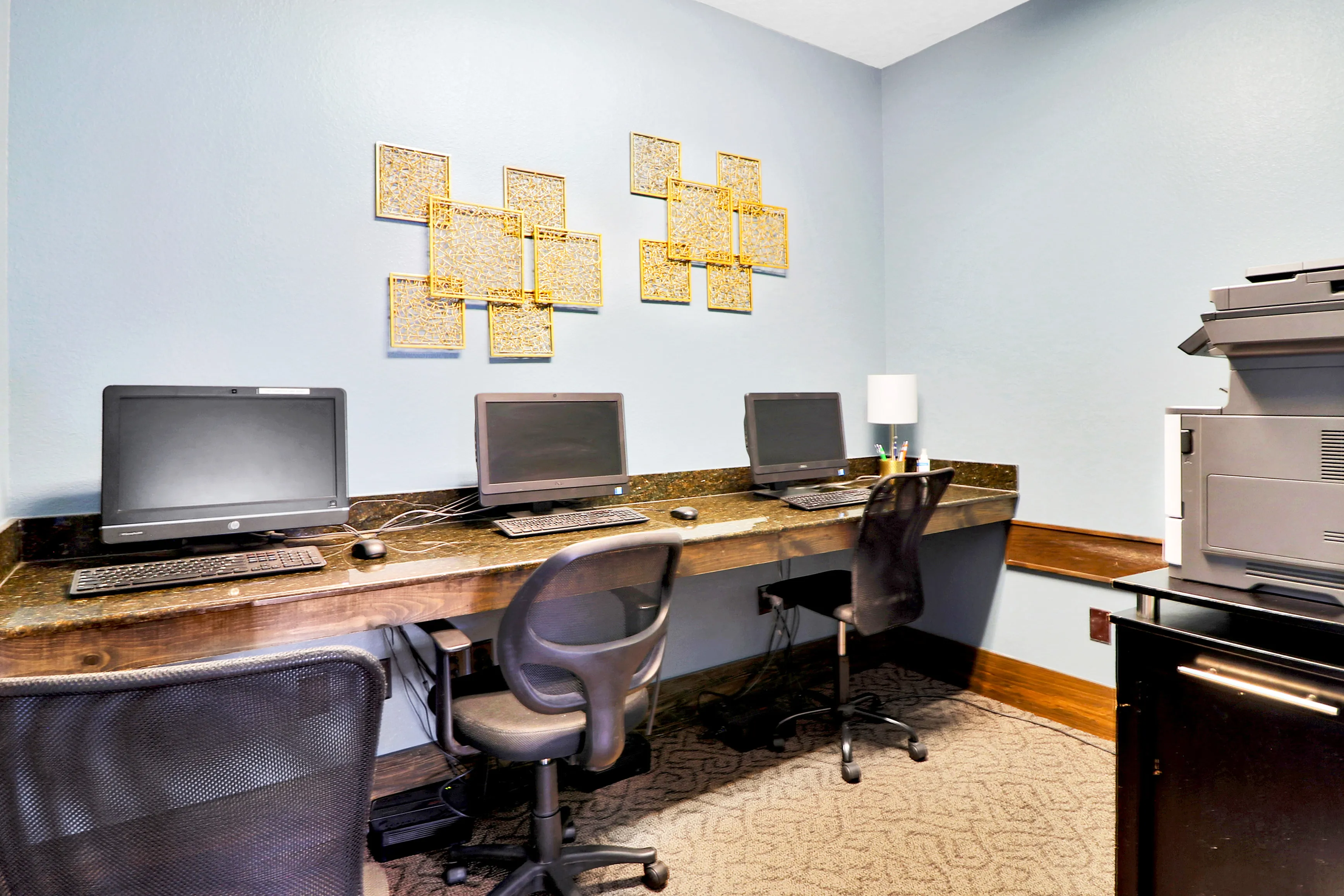 Inviting workspace with three computer stations, sleek decor, and vibrant wall art, perfect for productivity and creativity.