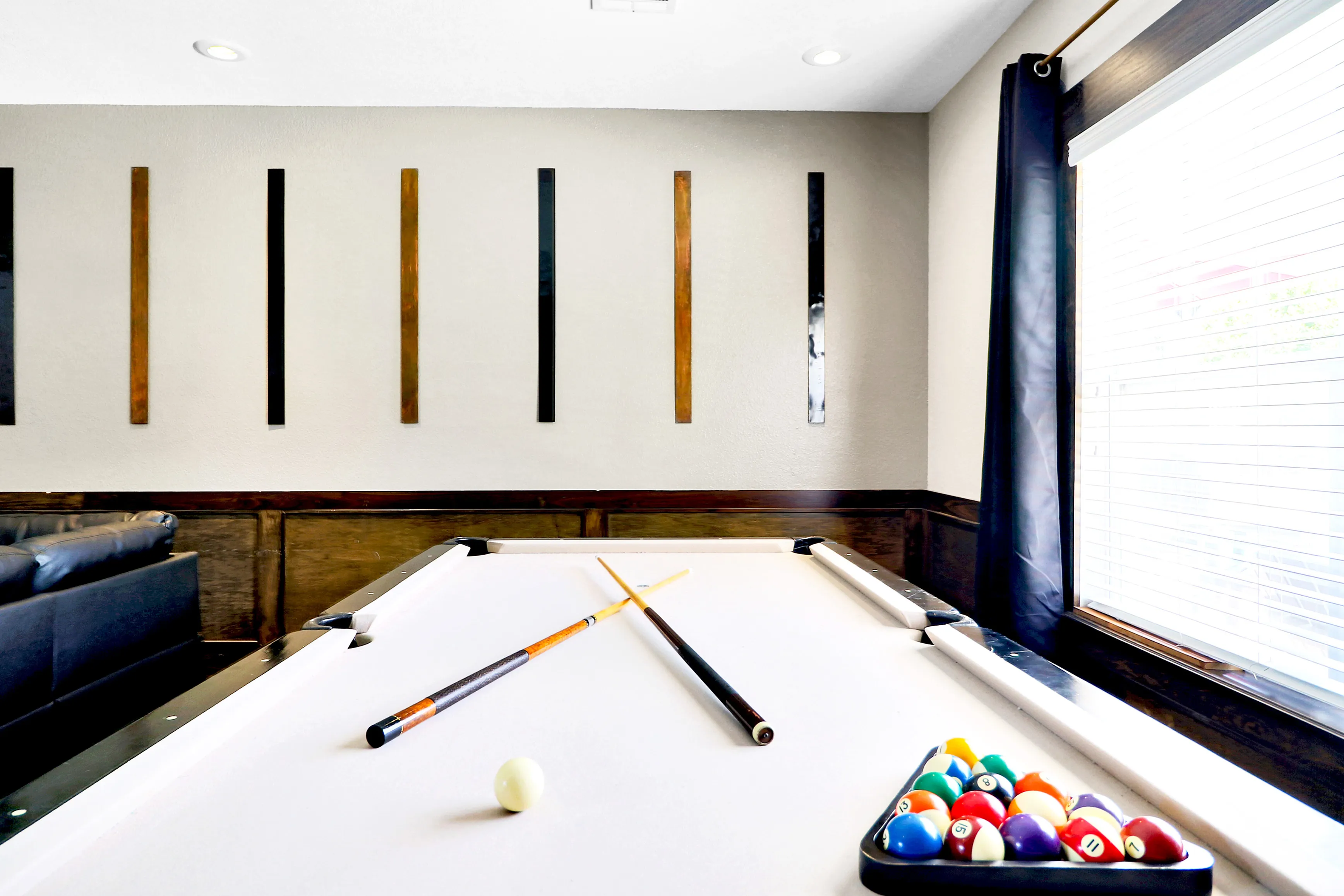 Chic game room with a sleek billiard table, perfect for entertainment and relaxation, brightened by natural light from large windows.