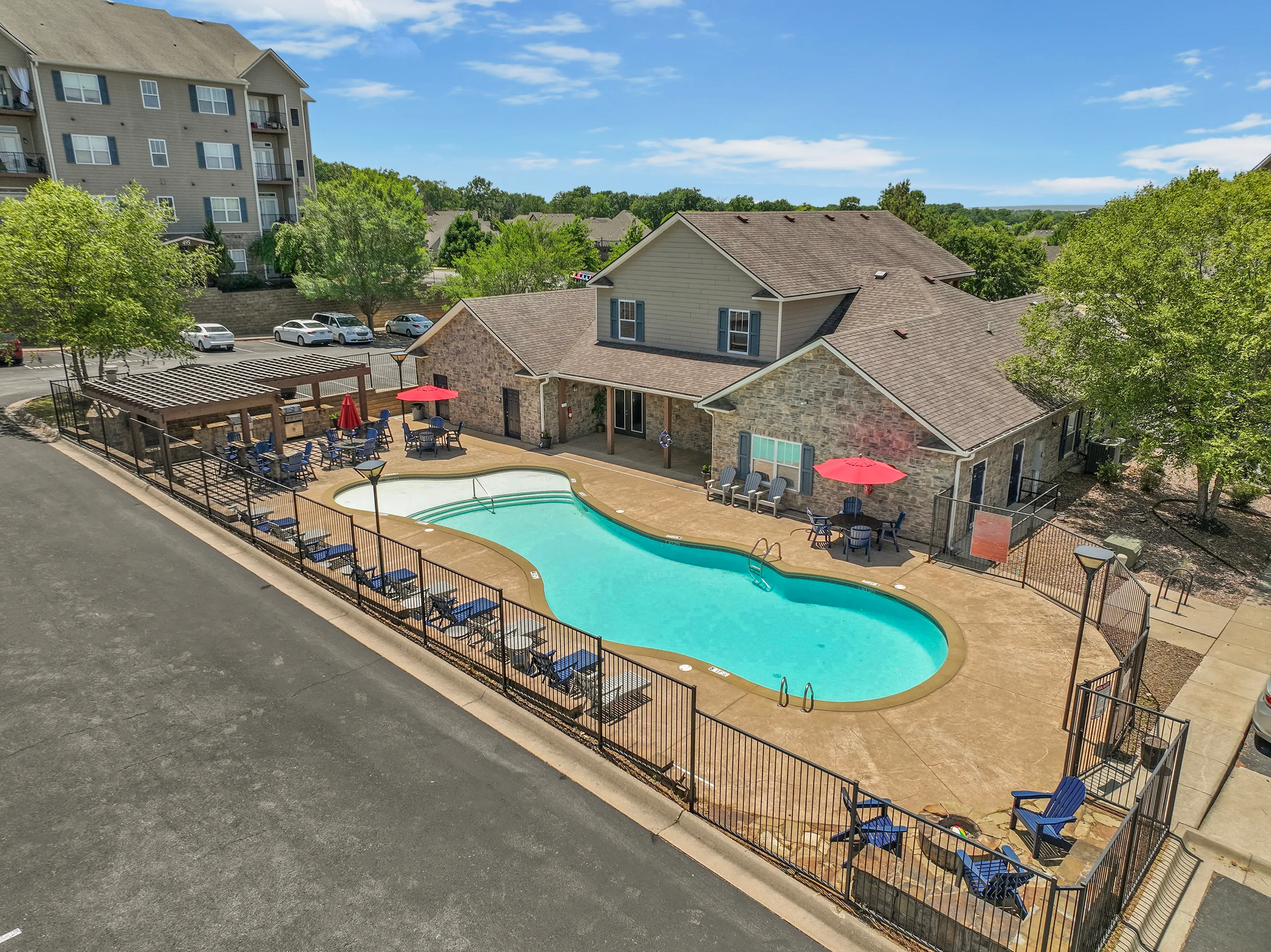 Inviting apartment complex with a sparkling pool, surrounded by sun loungers and shaded seating areas, perfect for relaxation and socializing.