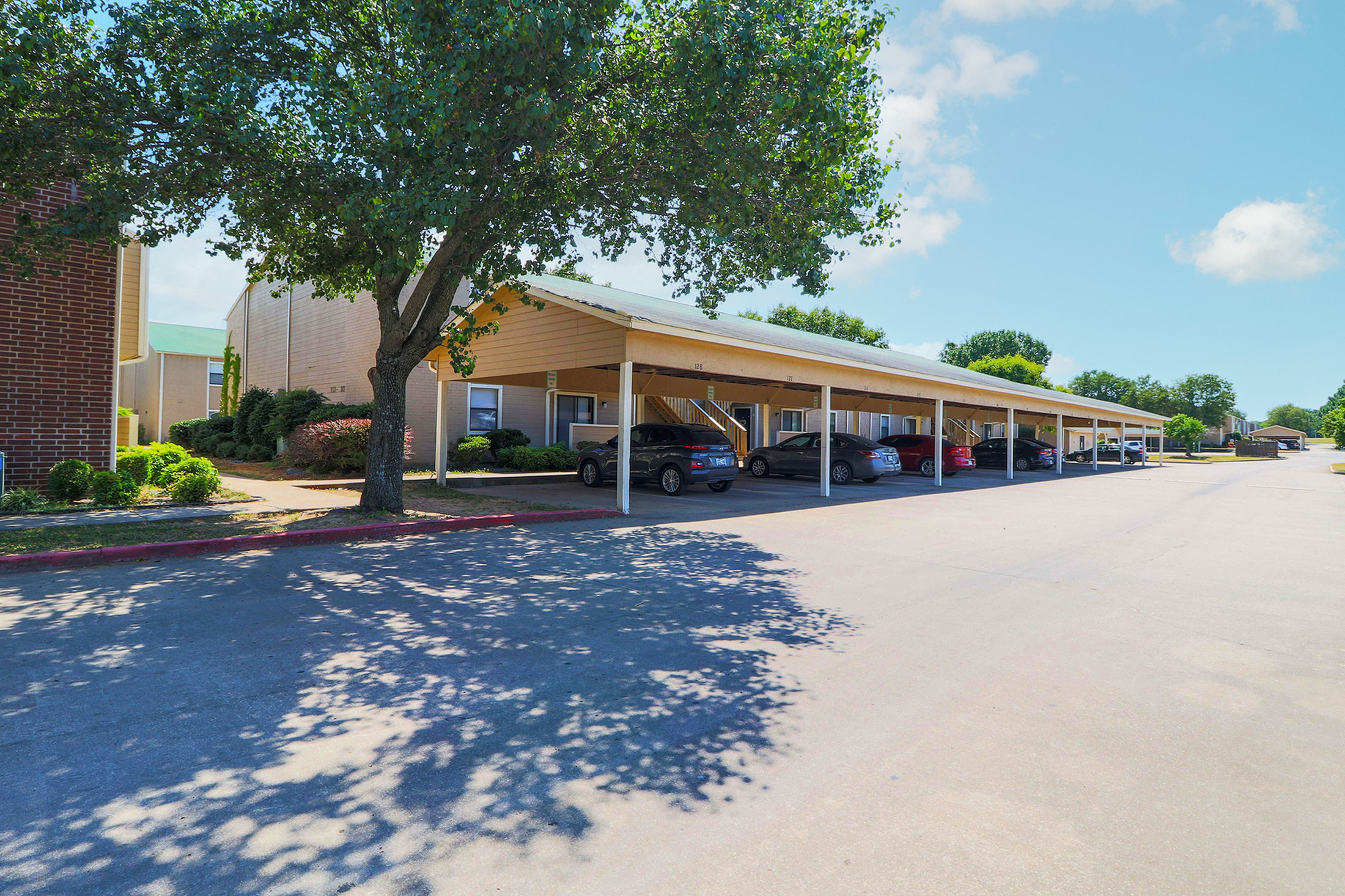 Charming apartment complex with covered parking and lush greenery, offering a serene living experience.