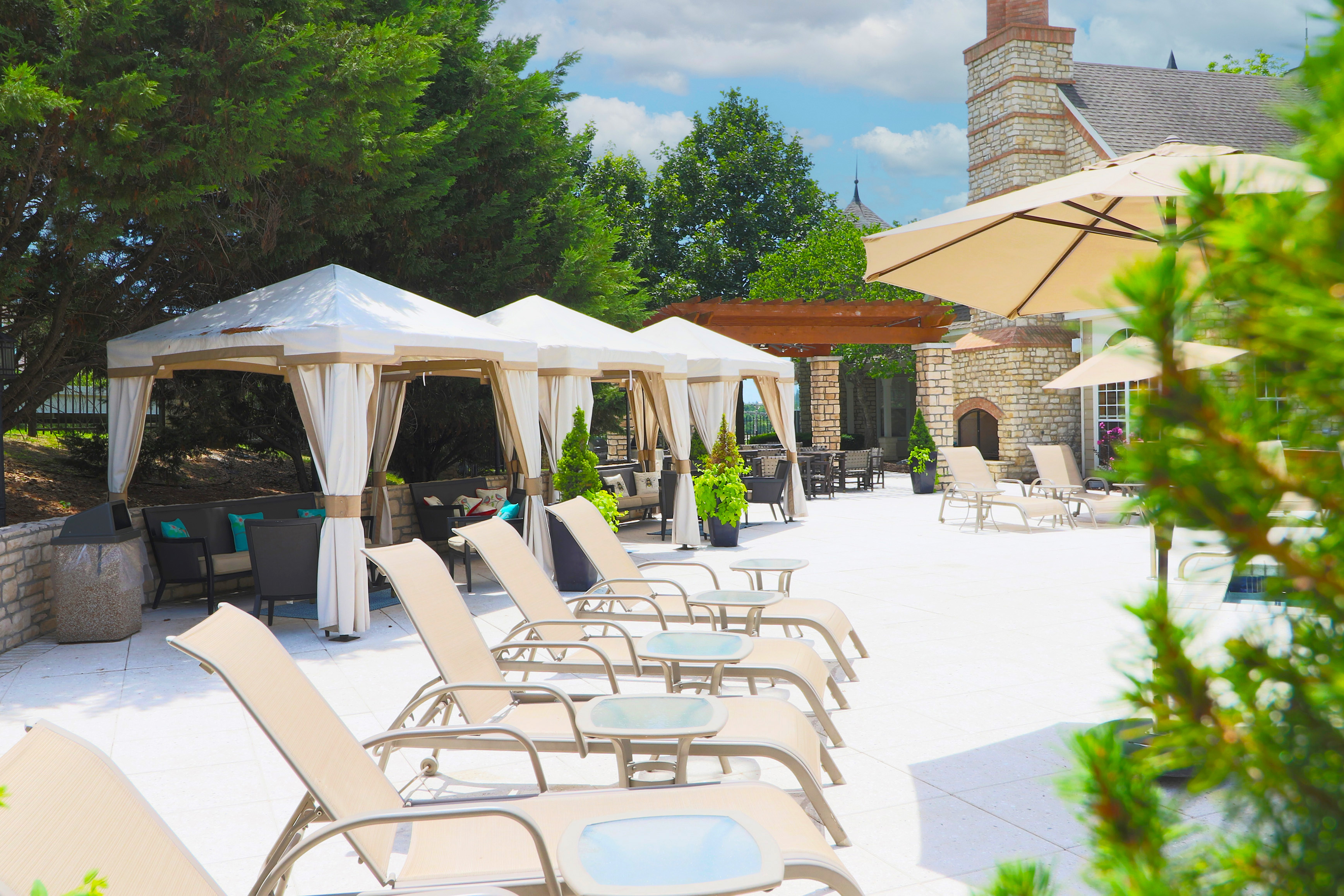 Luxurious outdoor patio with elegant cabanas, stylish lounge chairs, and vibrant greenery for a perfect relaxation spot.