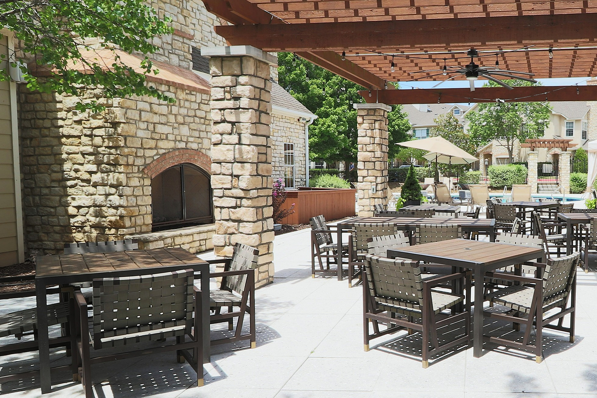 Charming outdoor patio with elegant pergola, stone pillars, and modern dining furniture surrounded by lush greenery; perfect for alfresco dining and relaxation.