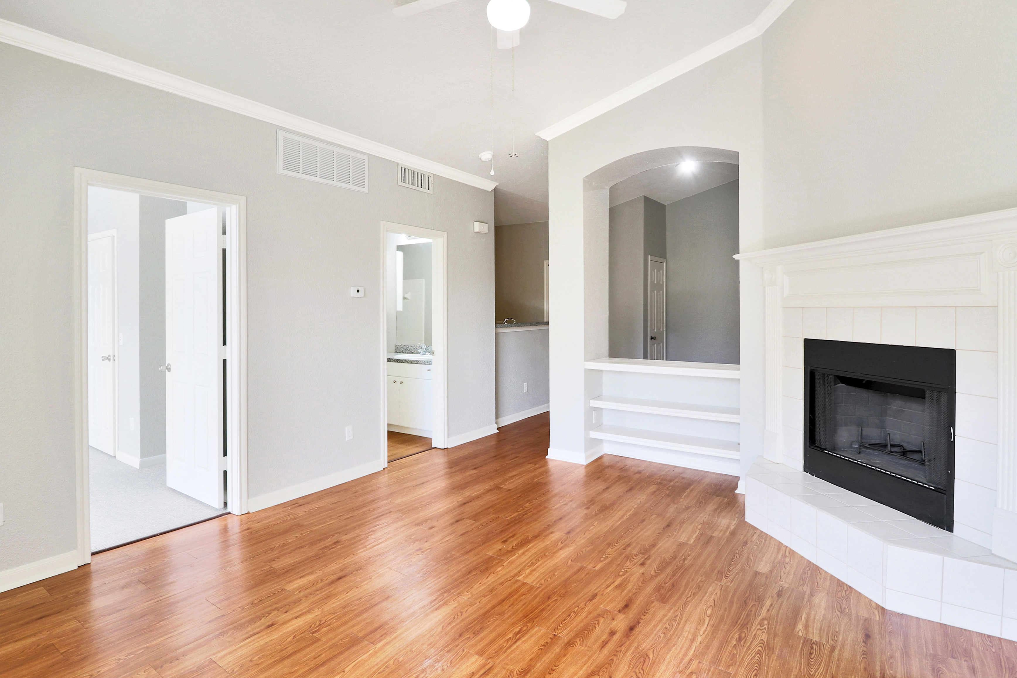 Bright and airy living room with elegant hardwood floors, featuring a cozy fireplace and built-in shelving, offering a warm and welcoming ambiance.