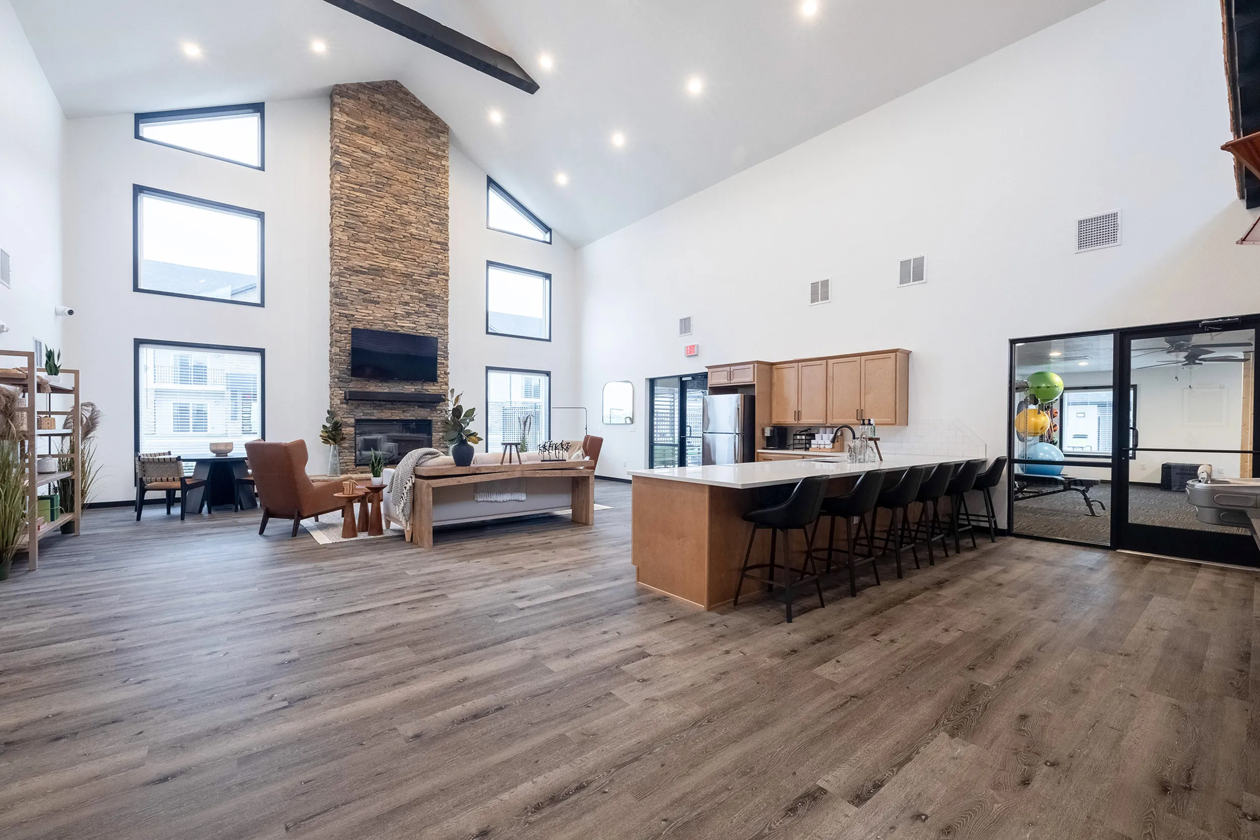 Spacious open-concept living room with modern stone fireplace, abundant natural light, and a sleek kitchen island with seating.
