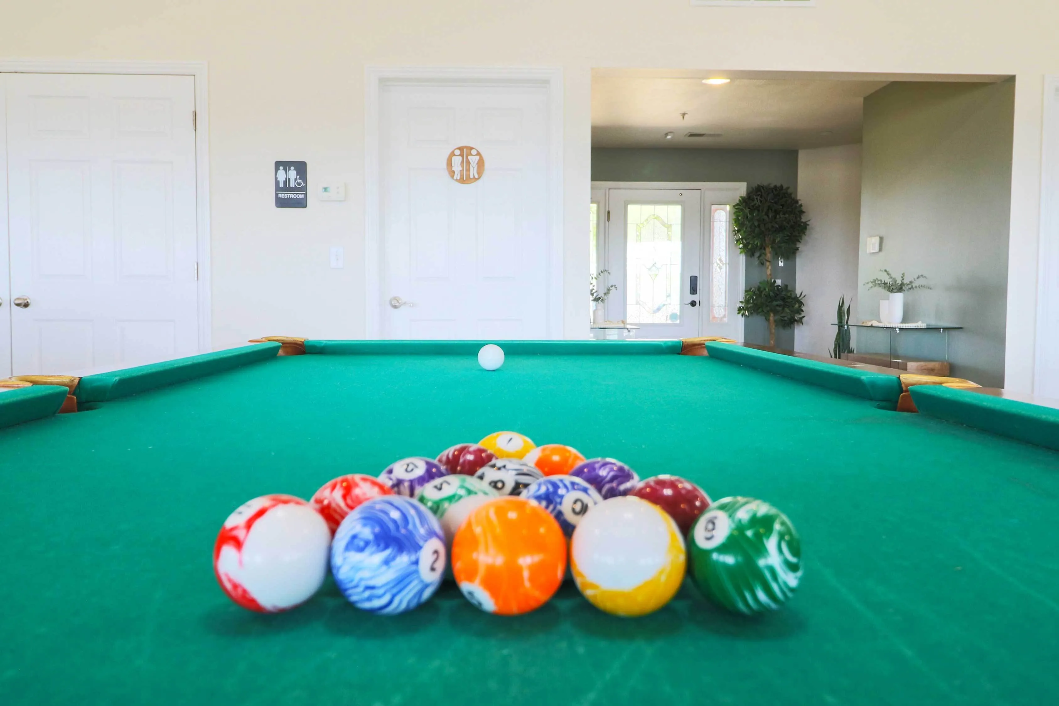 Inviting recreation room featuring a vibrant pool table with colorful billiard balls, set in a bright, welcoming space with modern decor and natural light.