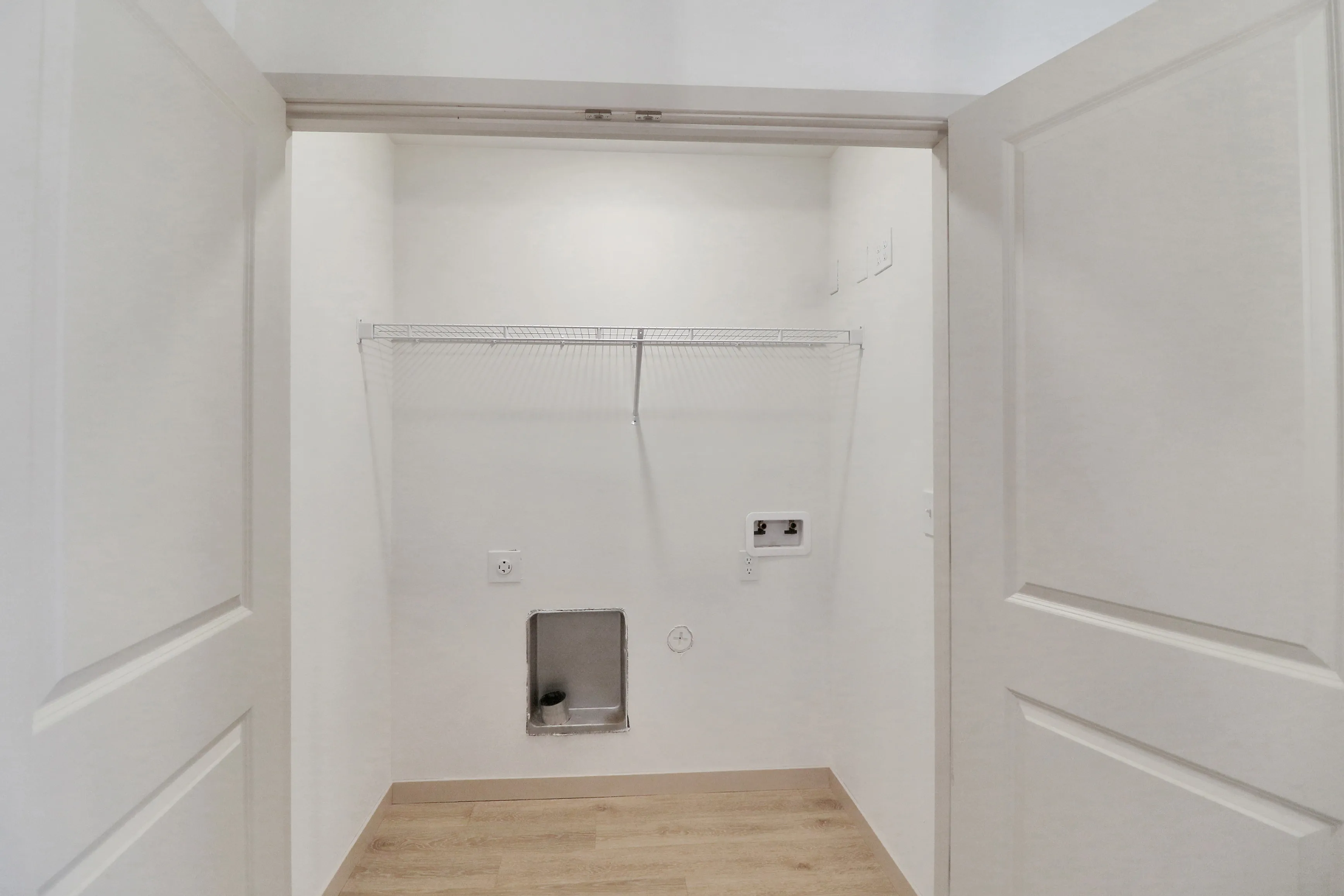 Modern laundry area with ample shelving and utility hookups, perfect for a convenient and tidy apartment living experience.