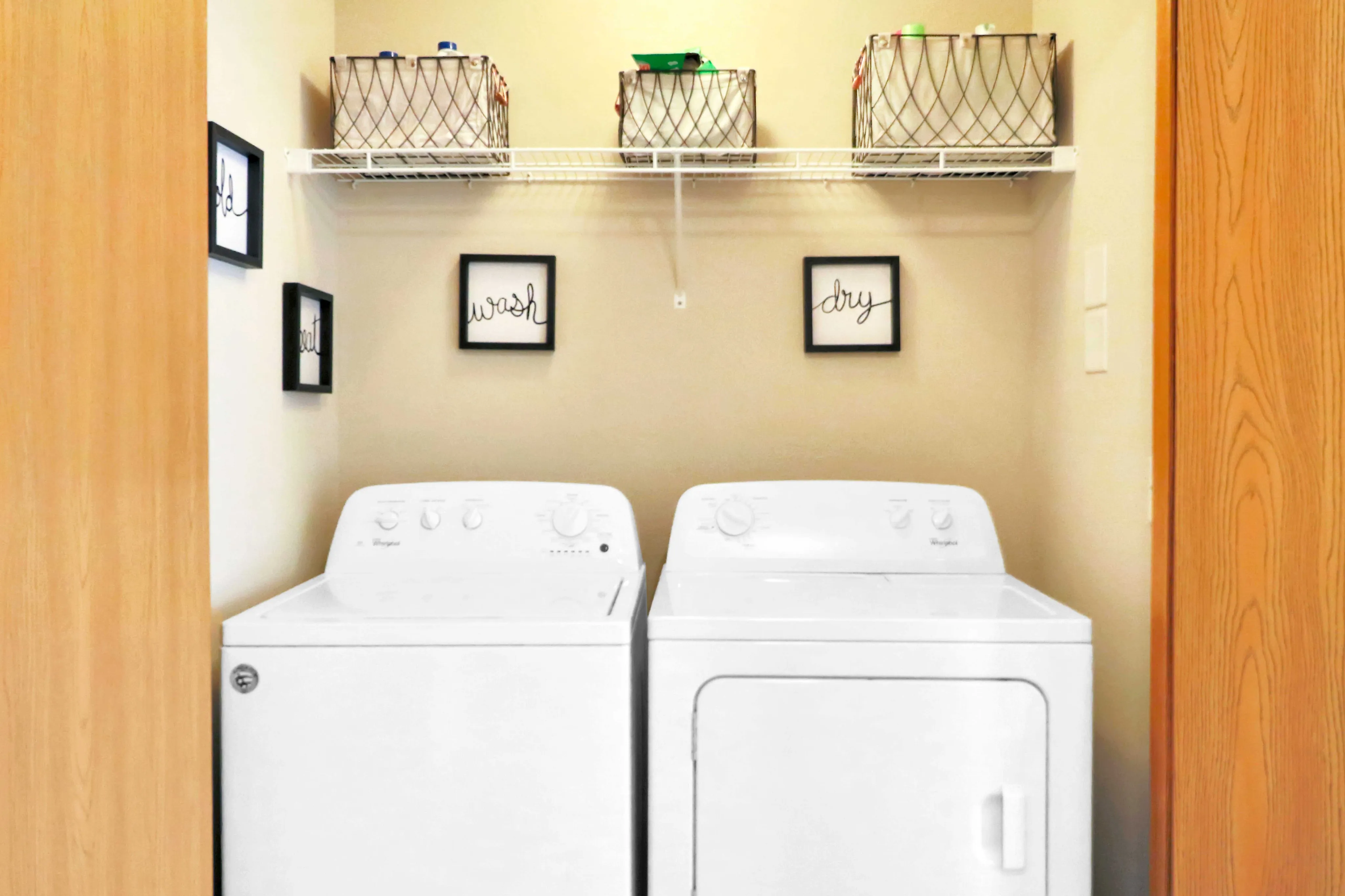 Charming laundry room with modern washer and dryer, elegant decor, and organized shelving.
