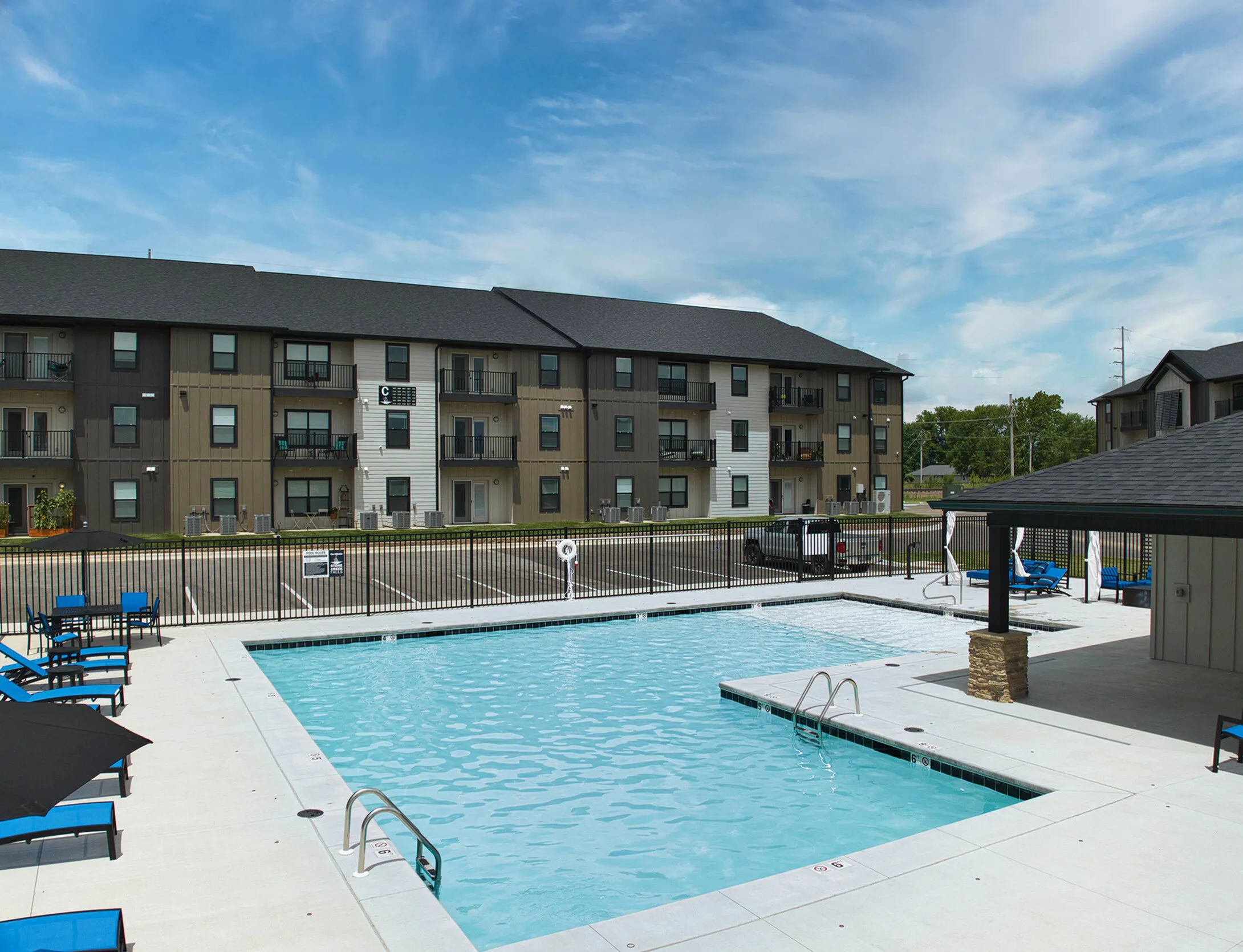 Chic apartment complex with a sparkling outdoor pool, surrounded by modern three-story buildings, perfect for stylish living.