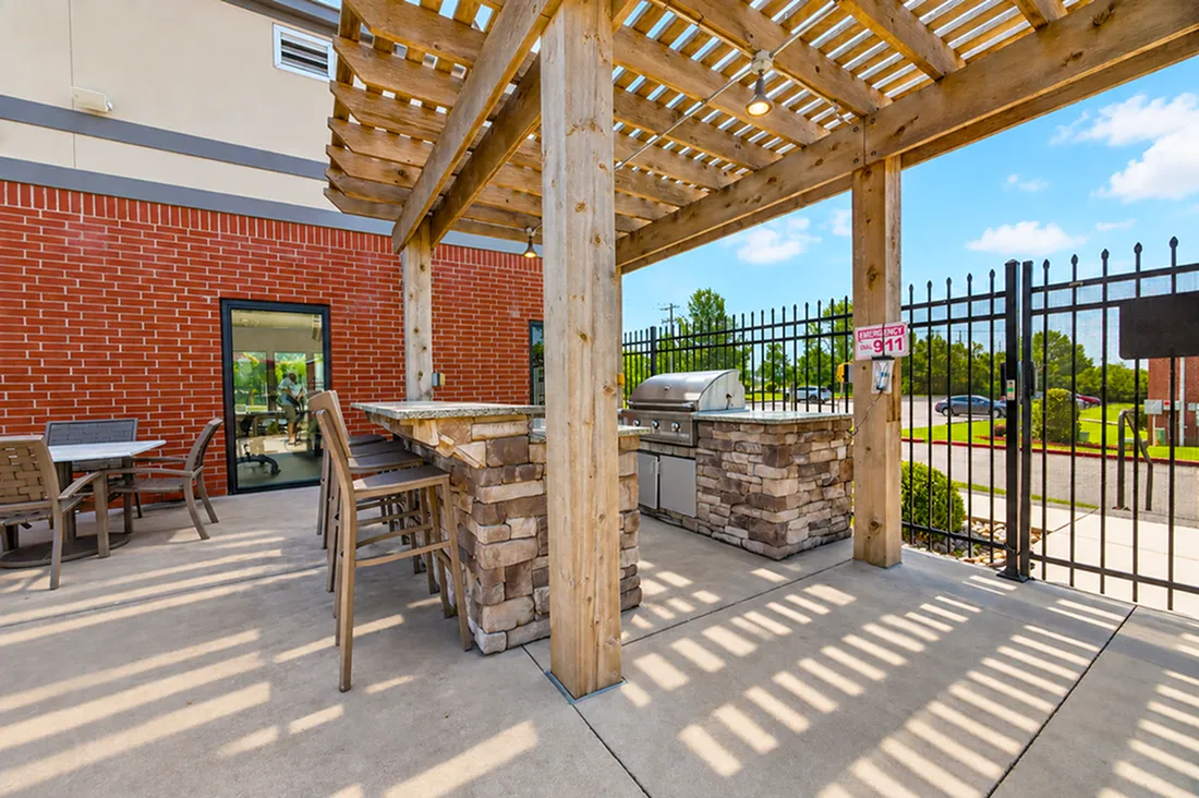 Inviting outdoor patio featuring a modern barbecue grill under a stylish wooden pergola, perfect for gatherings and relaxation.