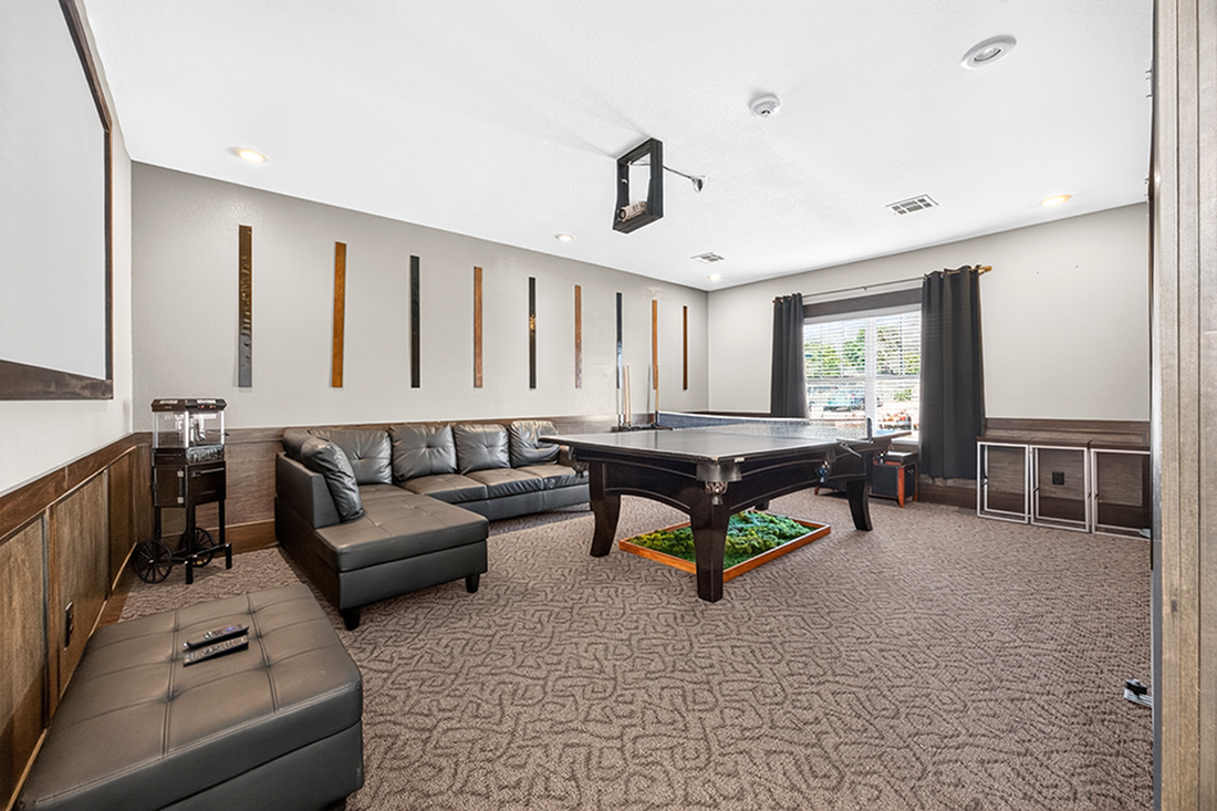 Chic game room featuring a sleek black sectional sofa, modern pool table, and stylish decor for ultimate relaxation and entertainment.