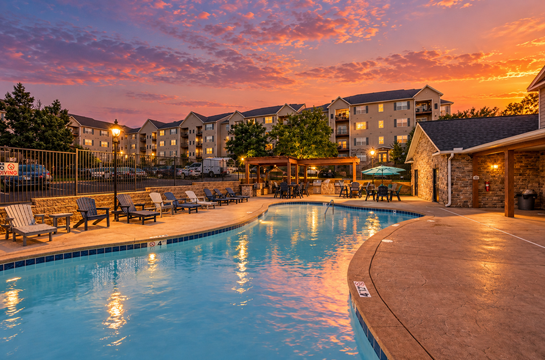Charming apartment complex with a sparkling pool and relaxing lounge area set against a stunning sunset backdrop.